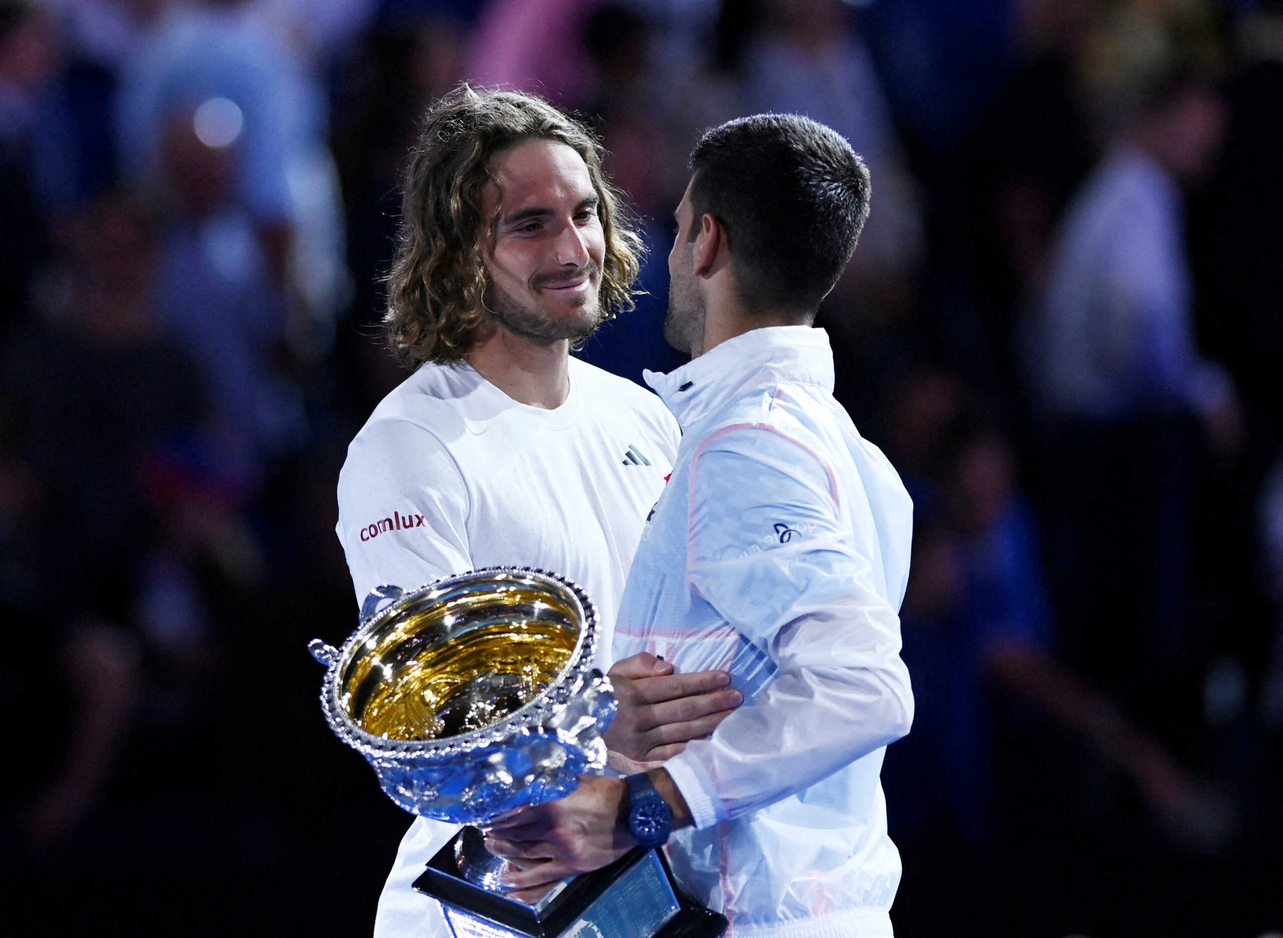 Tennis - Australian Open - Men's Singles Final - Melbourne Park, Melbourne, Australia - January 29, 2023 Winner, Serbia's Novak Djokovic hugs runner-up, Greece's Stefanos Tsitsipas as they hold their respective trophies after their final match REUTERS