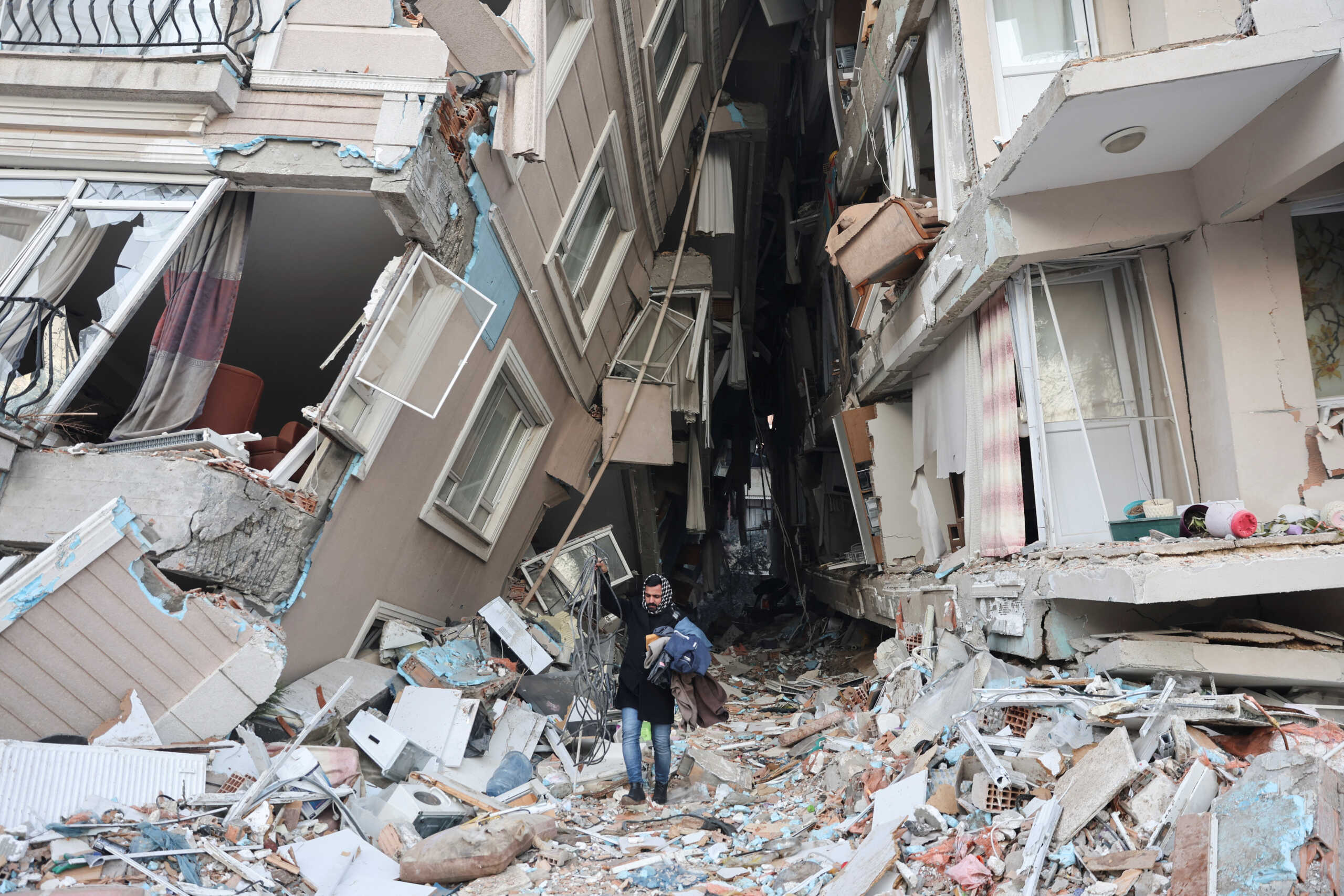 A survivor walks carrying belongings salvaged from his destroyed home, in the aftermath of a deadly earthquake in Hatay, Turkey February 9, 2023. REUTERS