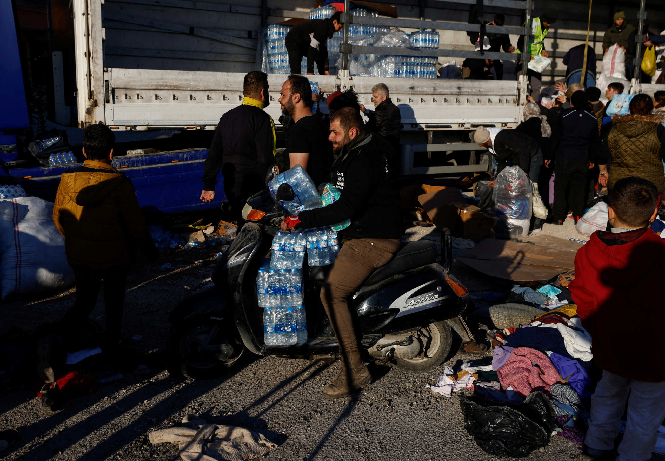 A man carries bottles of water received as aid on his scooter, in the aftermath of an earthquake, in Hatay, Turkey, February 8, 2023. REUTERS