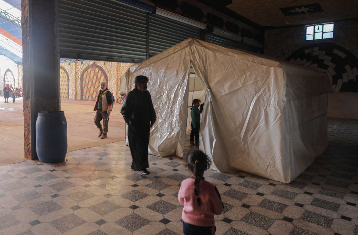 People stand near a tent as they take shelter inside a venue after they were struck by earthquakes in rebel-held Idlib, Syria February 21, 2023. REUTERS