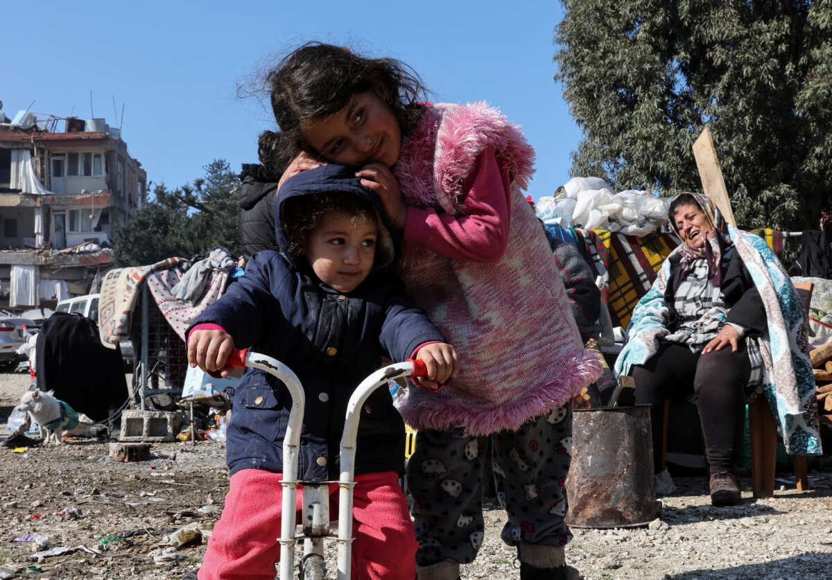 Children hug next to damaged buildings, as the search for survivors continues, in the aftermath of a deadly earthquake in Hatay, Turkey February 9, 2023. REUTERS