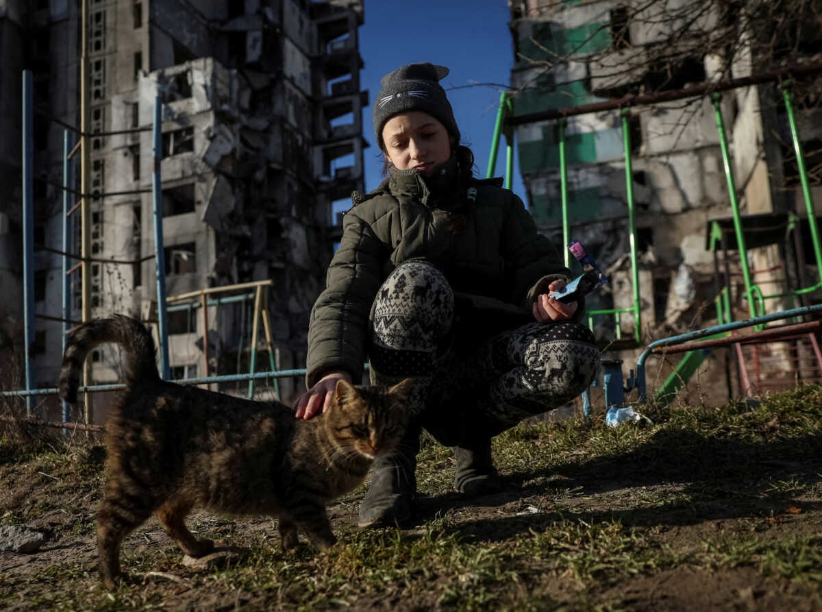 FILE PHOTO: Veronika Krasevych, an 11-year-old Ukrainian girl feeds a feral cat near her building destroyed by Russian military strike in the town of Borodianka, Ukraine February 15, 2023. REUTERS