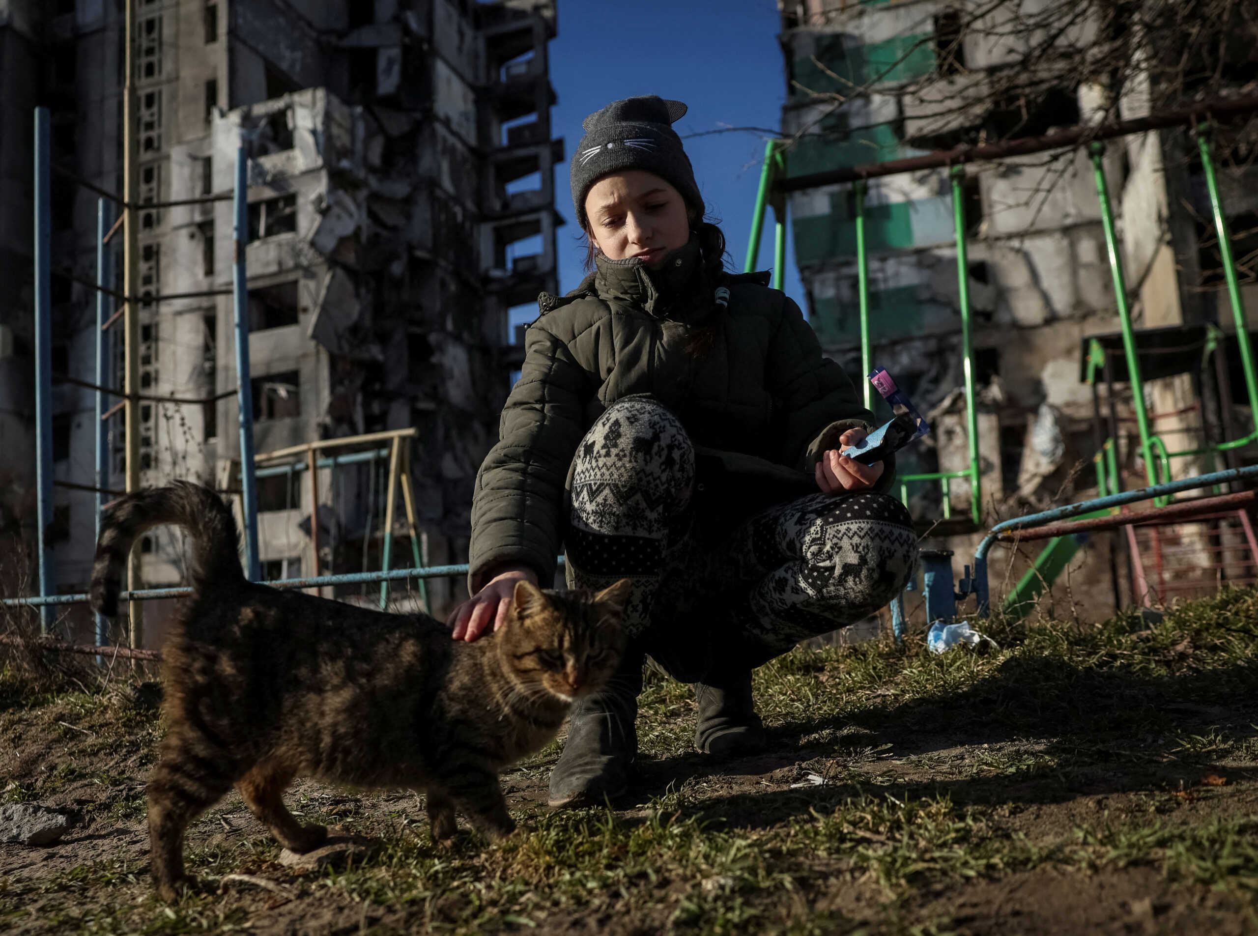 FILE PHOTO: Veronika Krasevych, an 11-year-old Ukrainian girl feeds a feral cat near her building destroyed by Russian military strike in the town of Borodianka, Ukraine February 15, 2023. REUTERS
