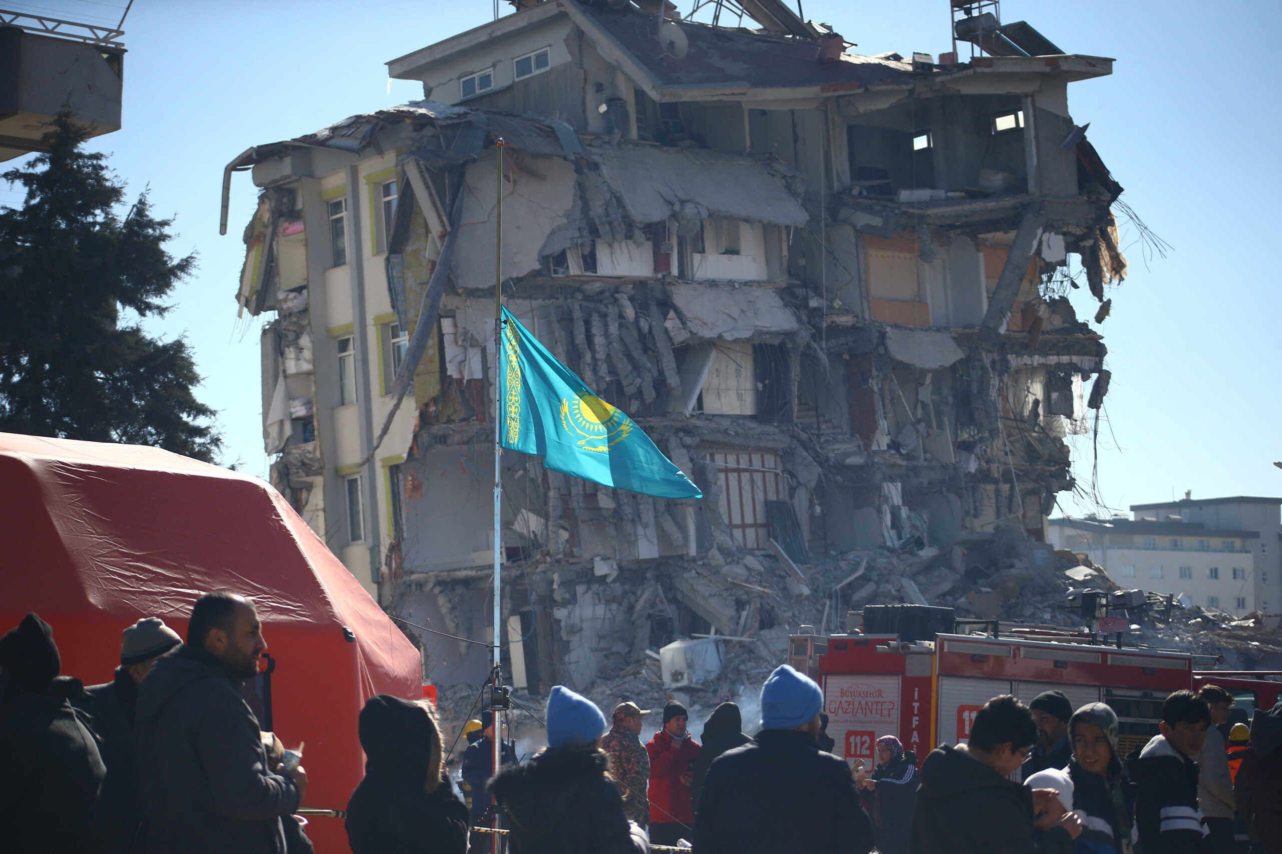 A flag of Kazakhstan is seen at half mast as a Kazak search and rescue team work at the site of a collapsed building in the aftermath of a deadly earthquake in Gaziantep, Turkey February 9, 2023. REUTERS