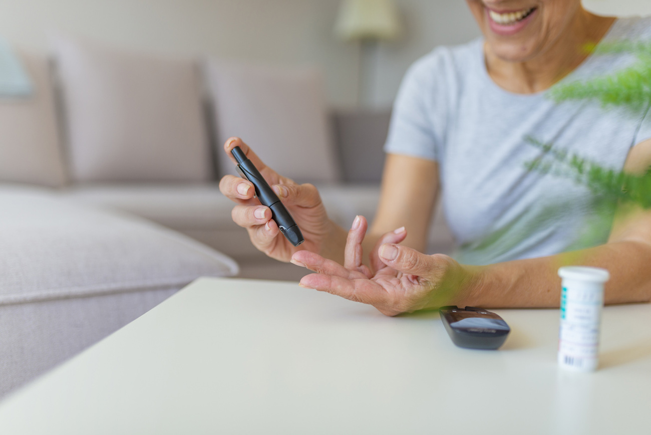 Close-up photo with a woman who is testing her level of glucose in her blood. Diabetes doing blood glucose measurement. Woman using lancet and glucometer.