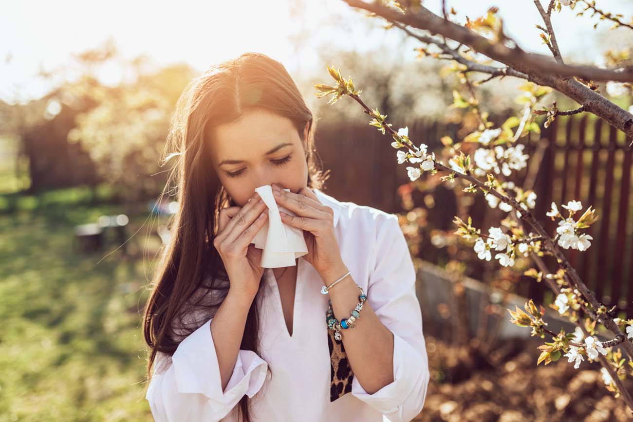 Attractive young adult woman coughing and sneezing outdoors. Sick people allergy or virus influenca concept.