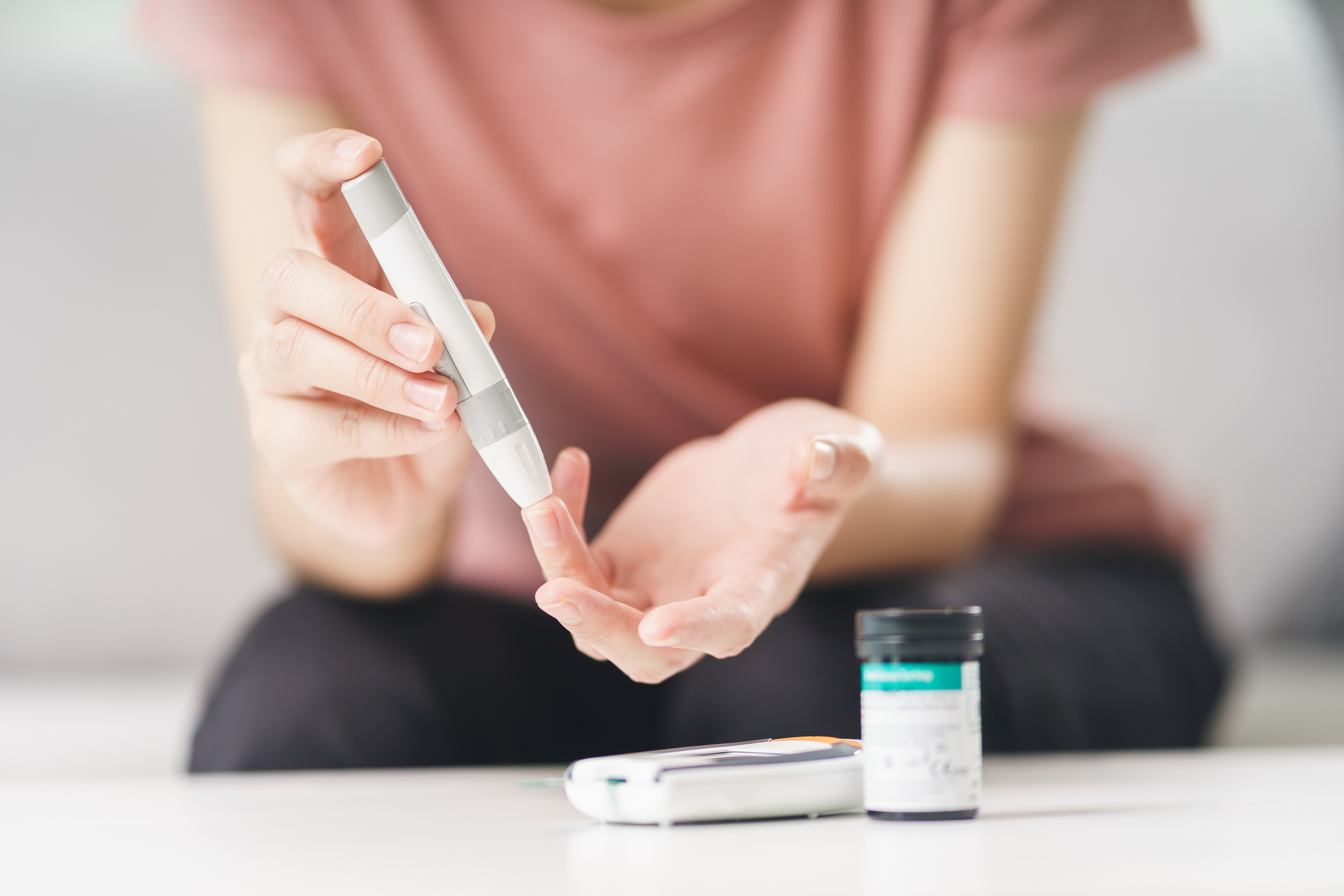 Asian woman using lancet on finger for checking blood sugar level by Glucose meter, Healthcare and Medical, diabetes, glycemia concept