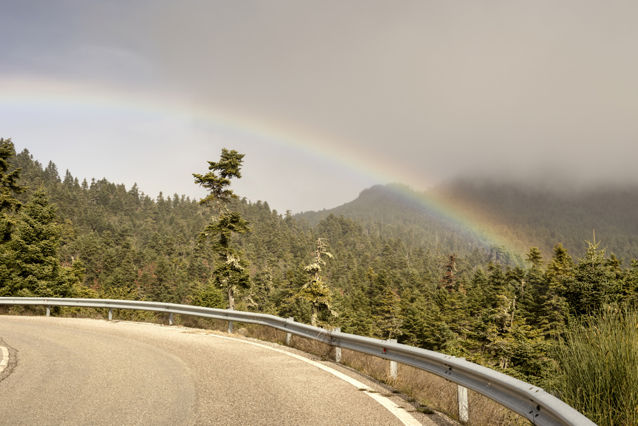 The mountain road in the forest and a rainbow