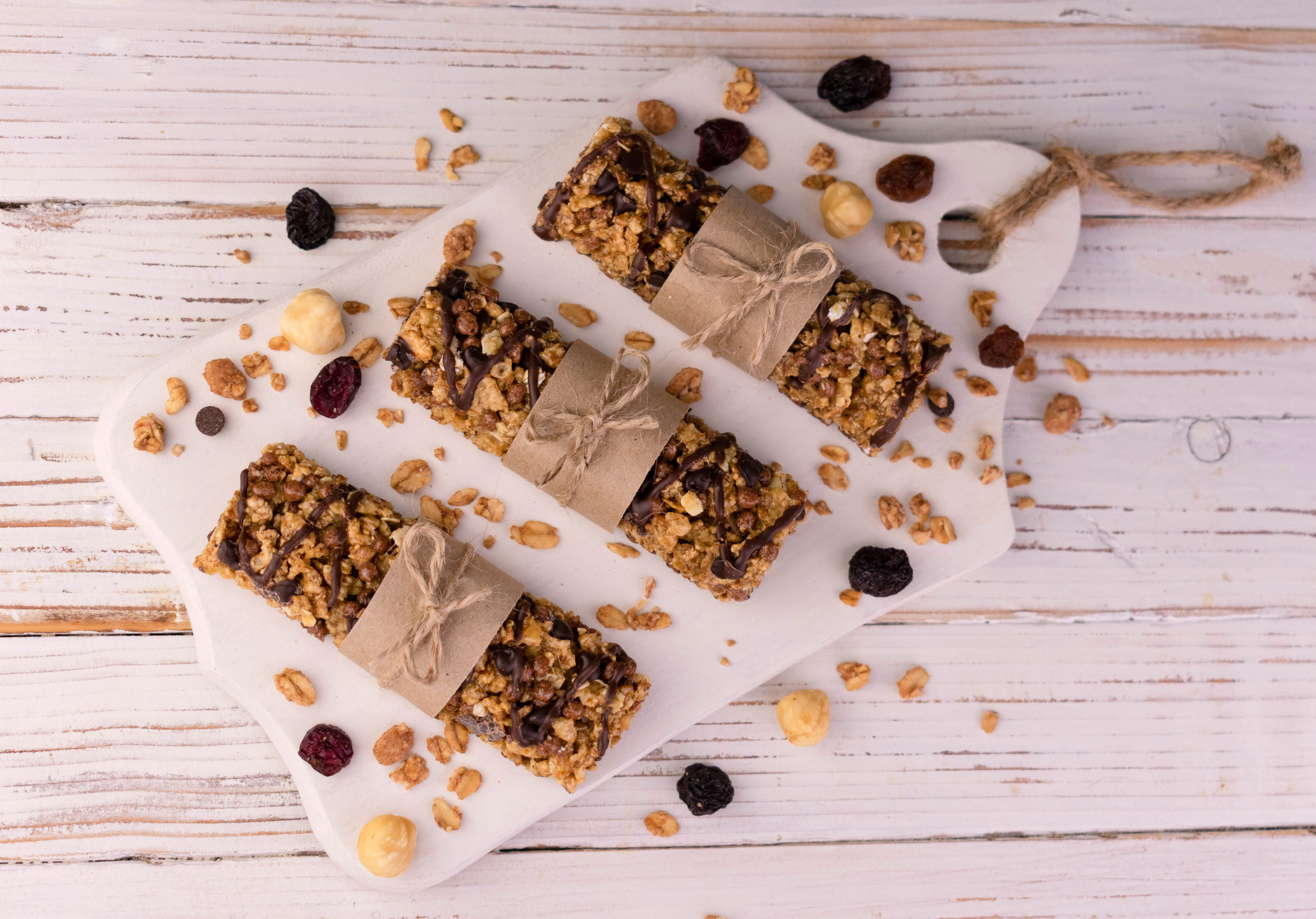 Three granola cereal bars on a white wooden background. Flat lay.
