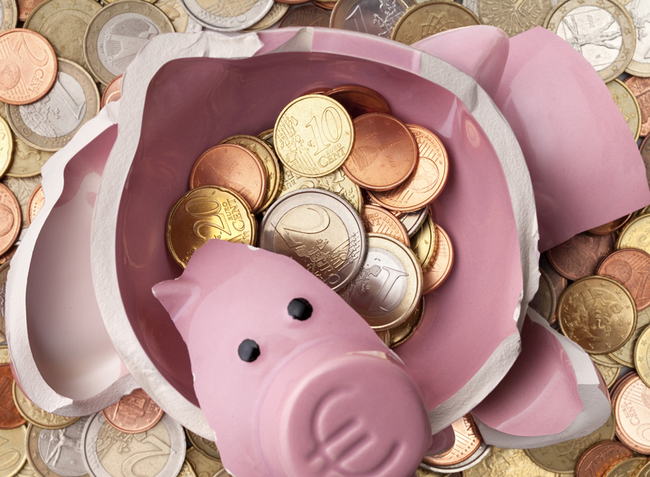 Savings. Broken piggy bank with euro coins.