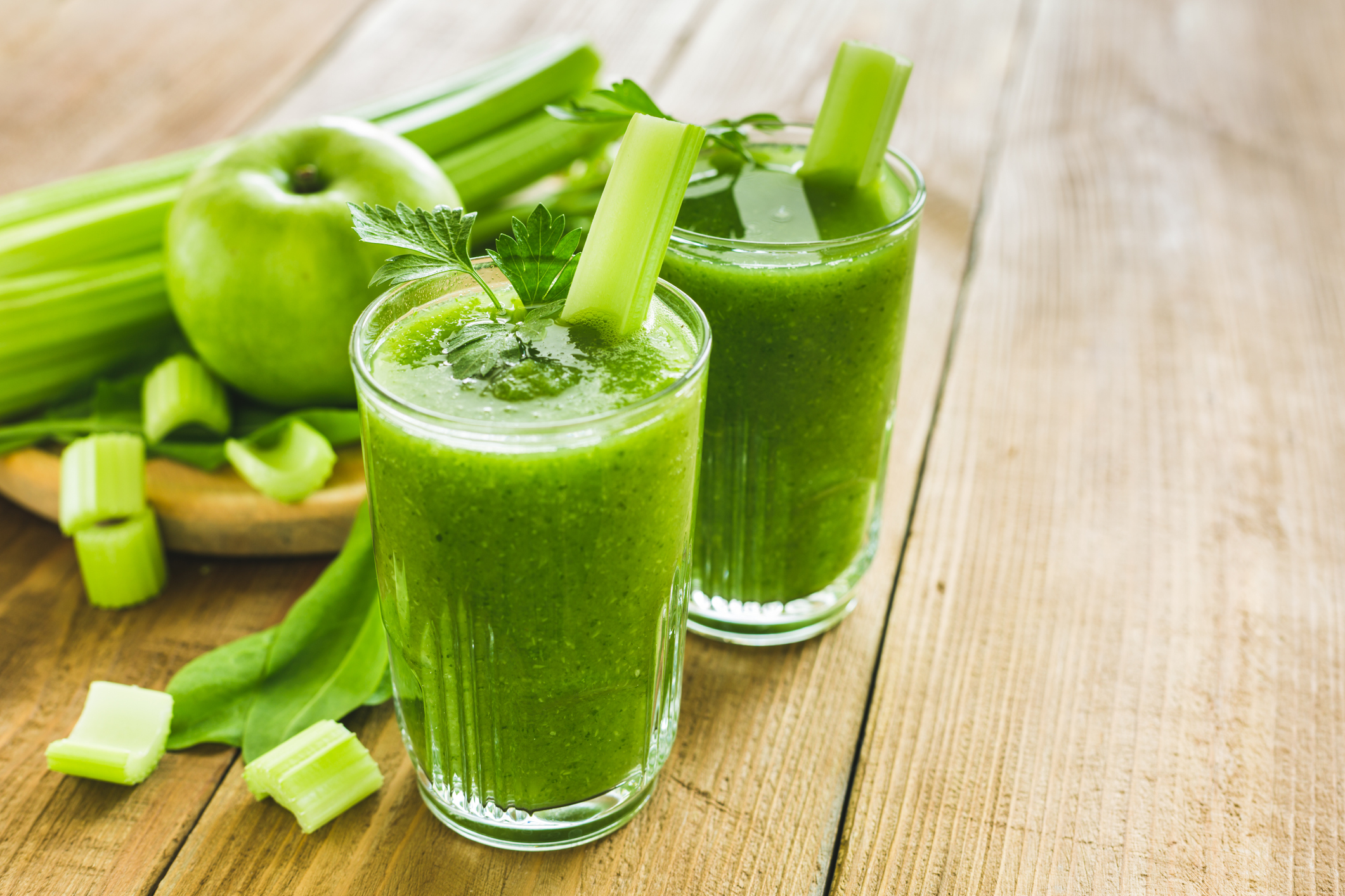 Green smoothie with celery, spinach and apple in two glasses
