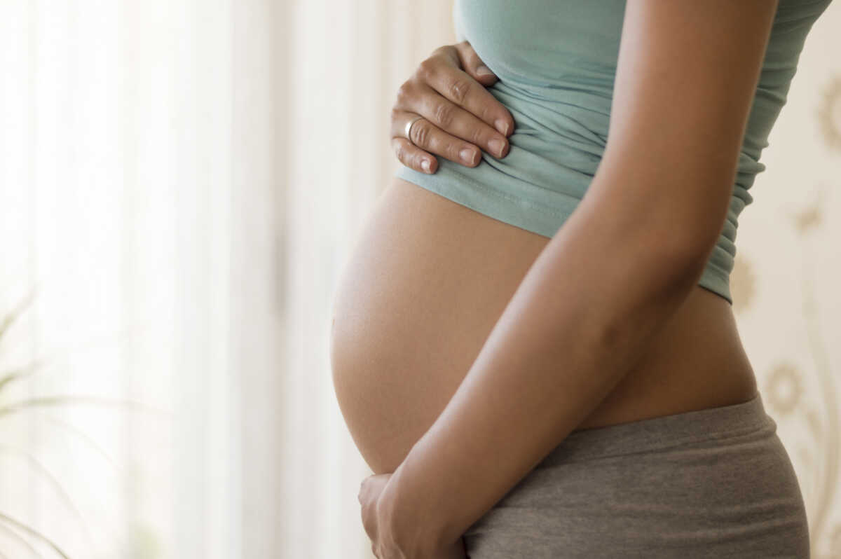 Pregnant's woman touching her belly with her hands.