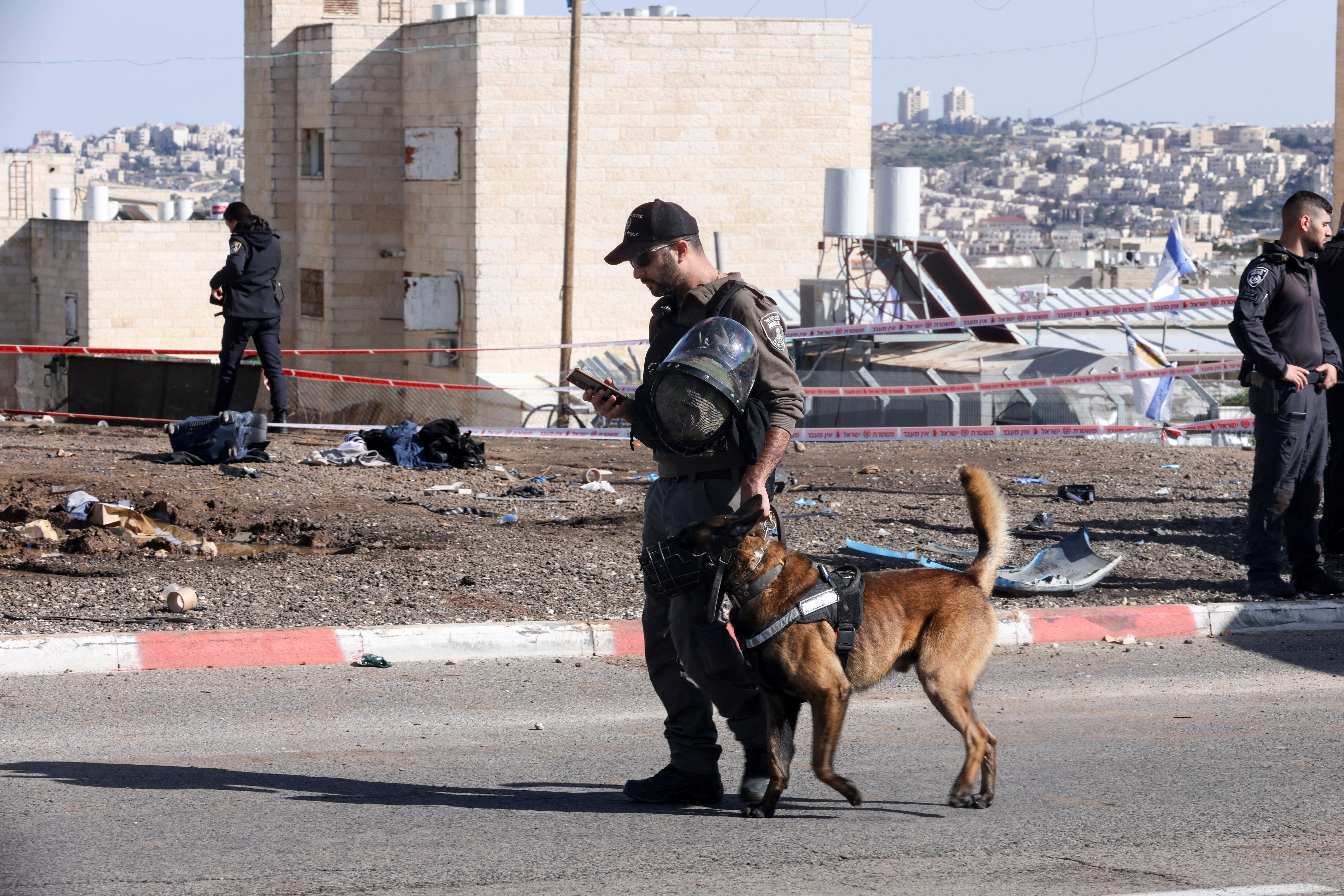 Israeli border police officer walks with his dog as they work at the scene where a suspected ramming attack took place in Jerusalem, February 10, 2023. REUTERS