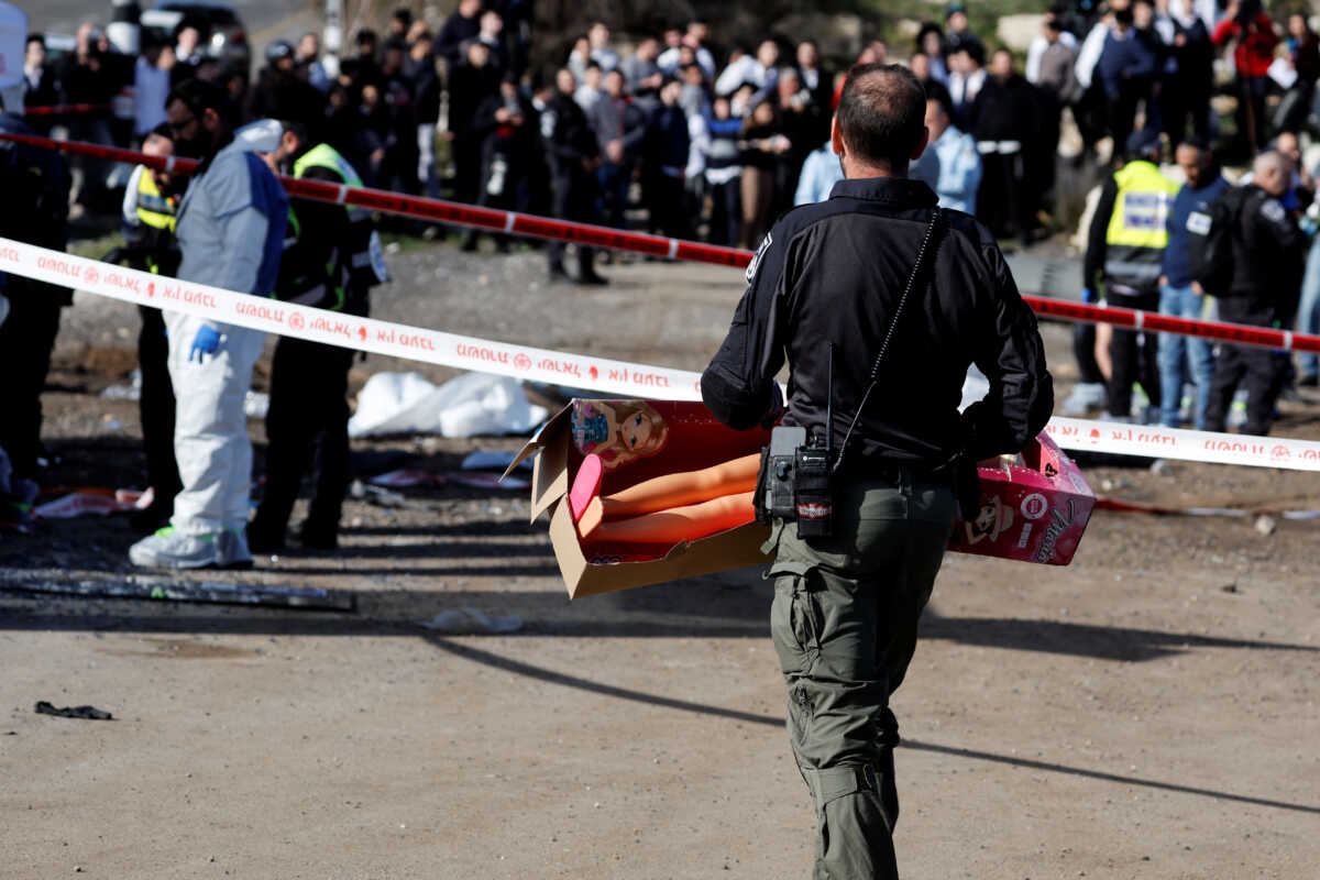 An Israeli policeman carries a big toy doll from the scene where a suspected ramming attack took place in Jerusalem February 10, 2023. REUTERS