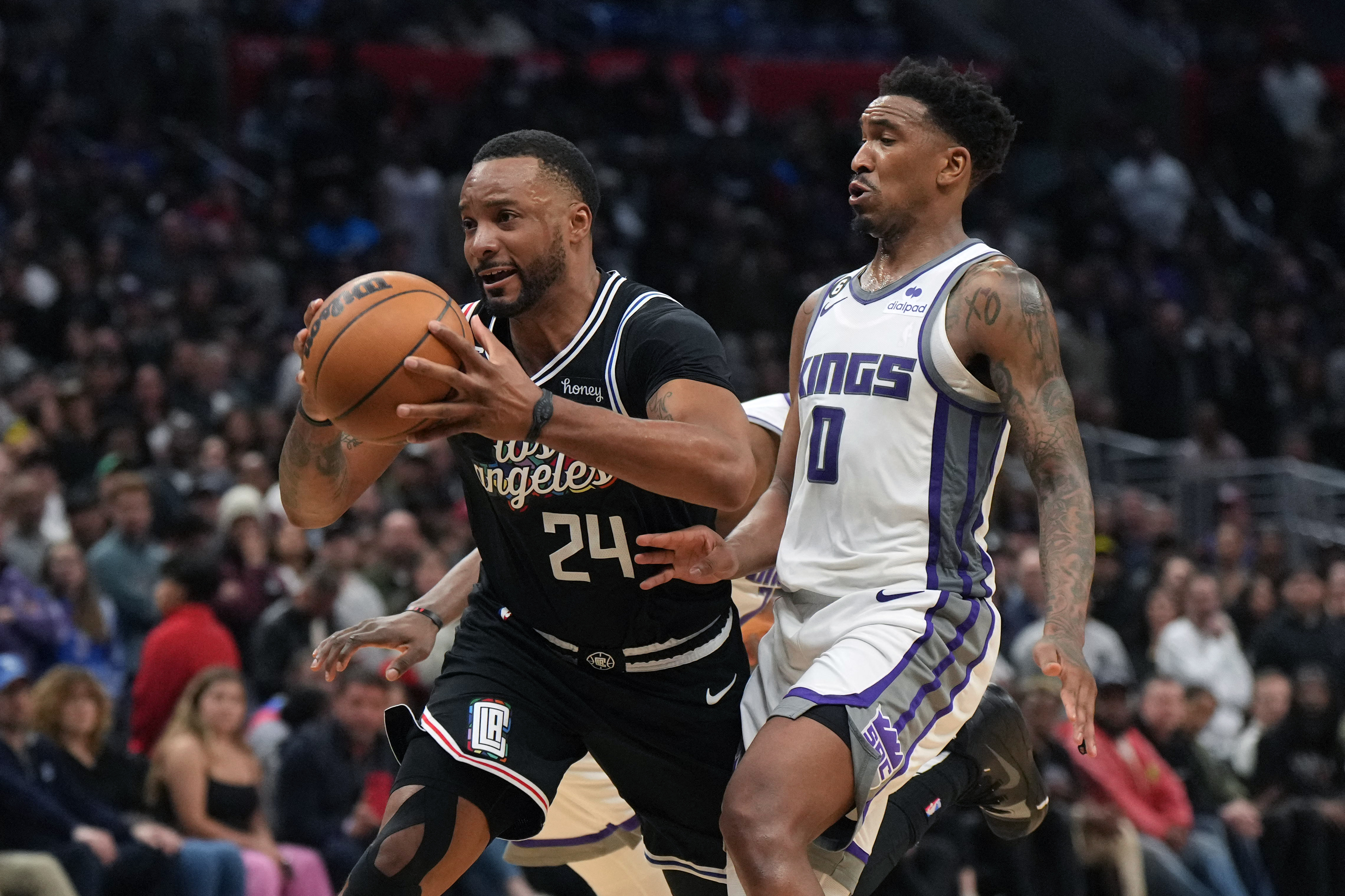 Feb 24, 2023; Los Angeles, California, USA; LA Clippers forward Norman Powell (24) is defended by Sacramento Kings guard Malik Monk (0) in the second half at Crypto.com Arena. The Kings defeated the Clippers 176-175 in double overtime. Mandatory Credit: Kirby Lee-USA TODAY Sports