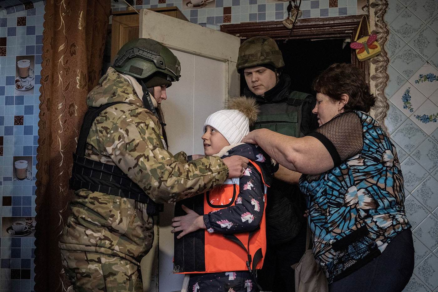 Valeria, a member of the White Angel unit of Ukrainian police officers who evacuates people from the frontline towns and villages, puts body armour on Vika Savchenko, 8, during her evacuation from her village of Zarichne, near the town of Lyman, amid Russia's attack on Ukraine, Donetsk region, Ukraine, February 20, 2023. REUTERS