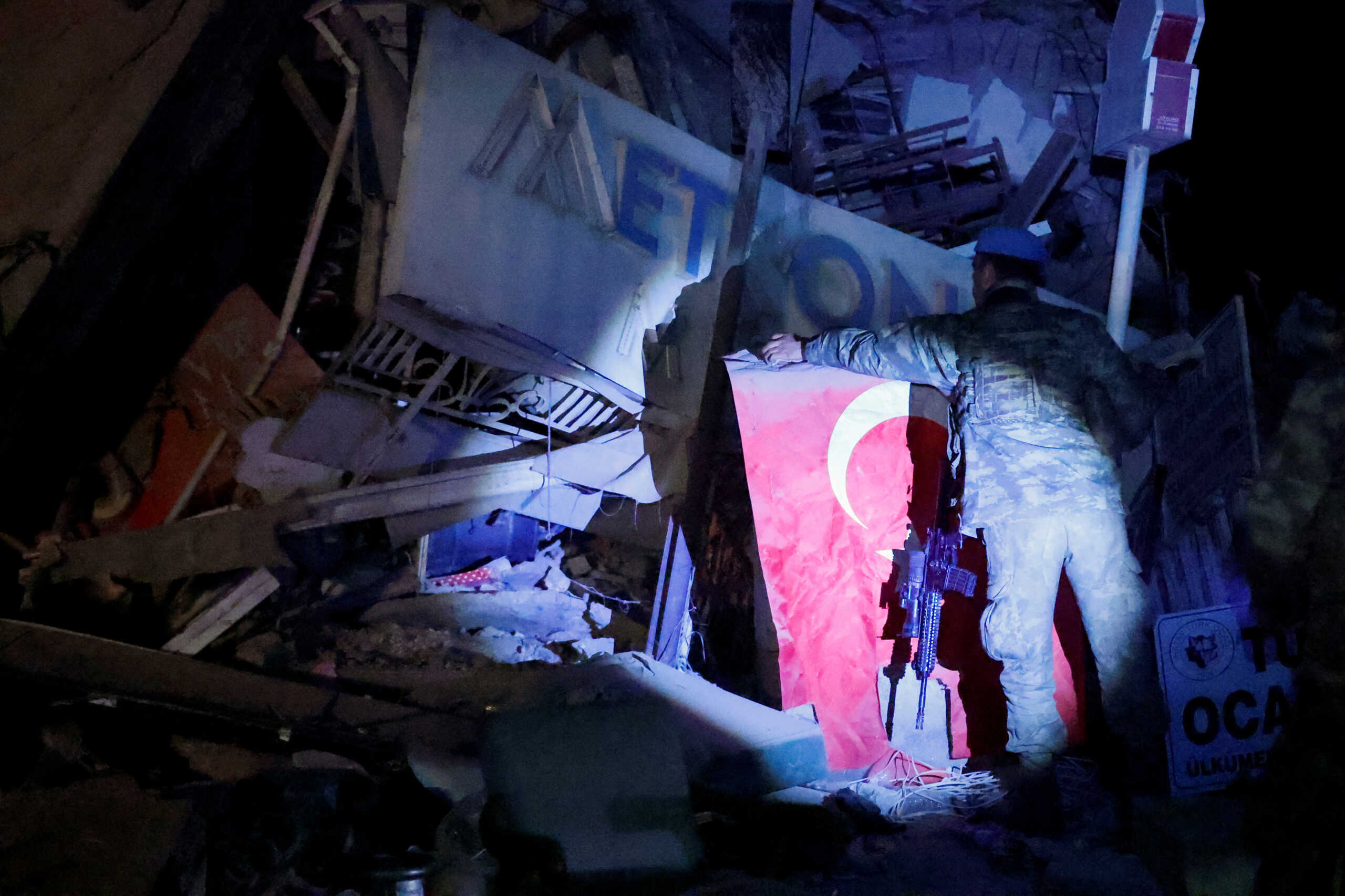 A soldier retrieves a Turkish flag from the rubble, in the aftermath of a deadly earthquake in Antakya, Hatay province, Turkey February 15, 2023. REUTERS