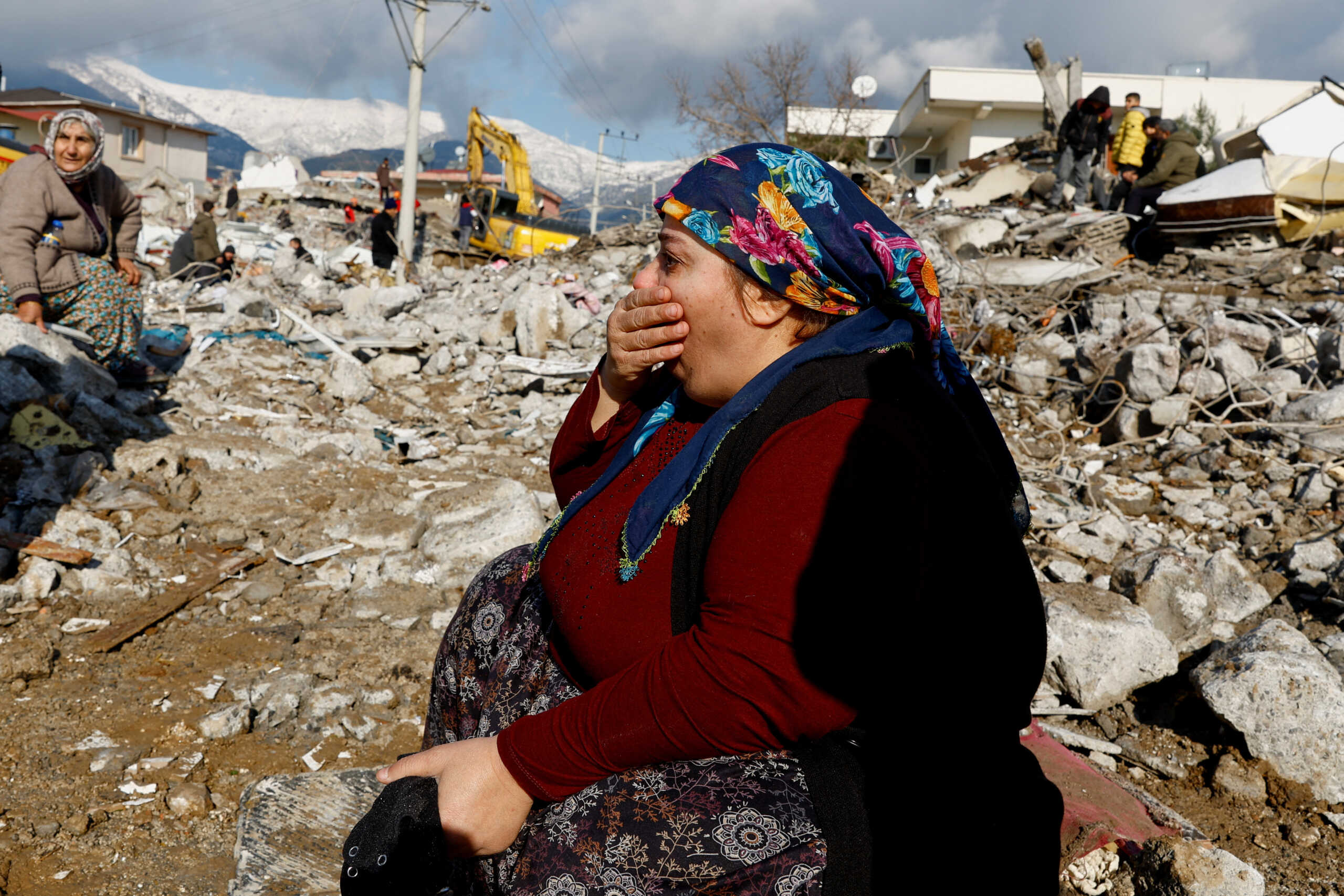 A woman gestures while sitting amidst rubble and damages following an earthquake in Gaziantep, Turkey, February 7, 2023. REUTERS