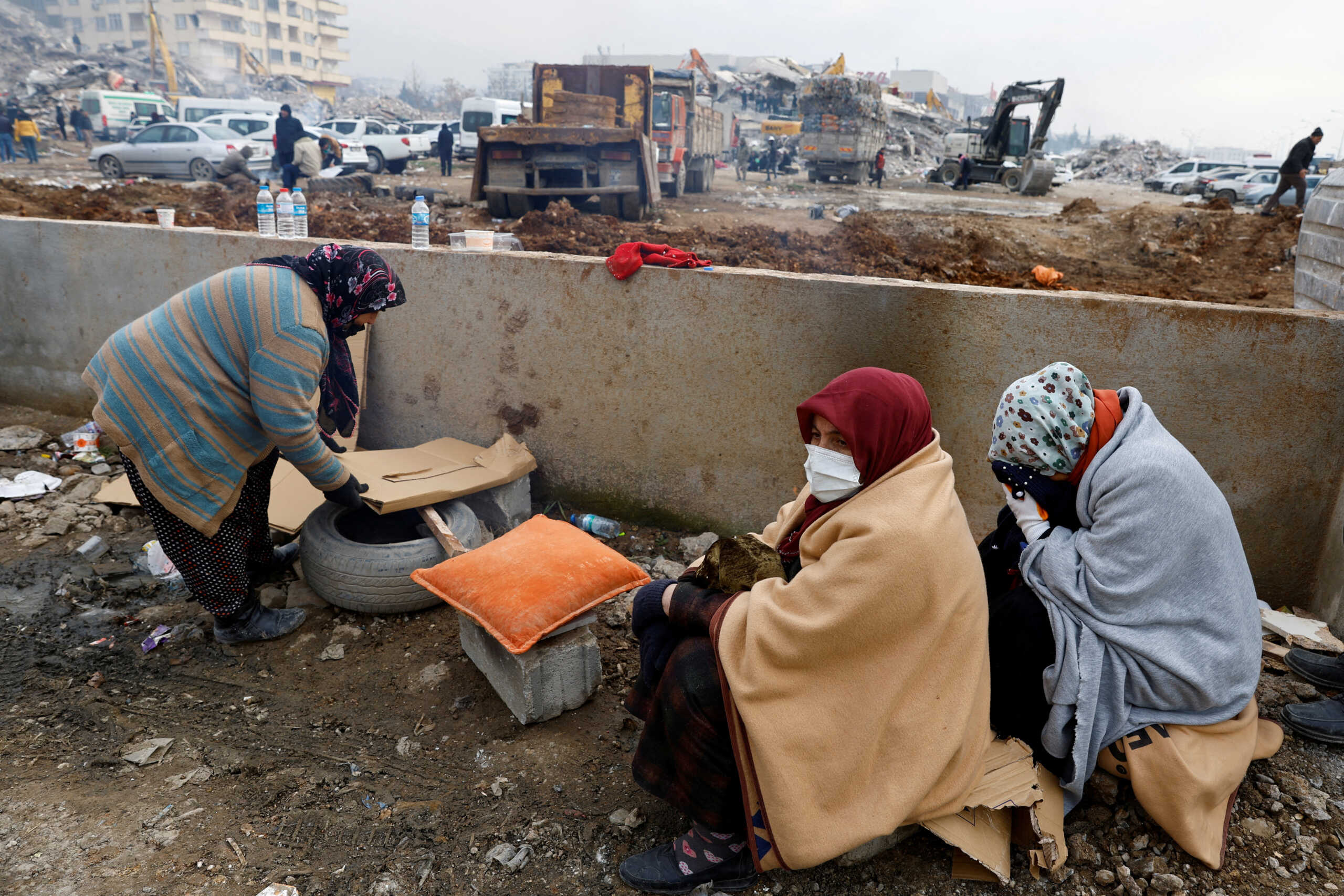 People sit next to rubble as the search for survivors continues, in the aftermath of a deadly earthquake in Kahramanmaras, Turkey February 10, 2023. REUTERS