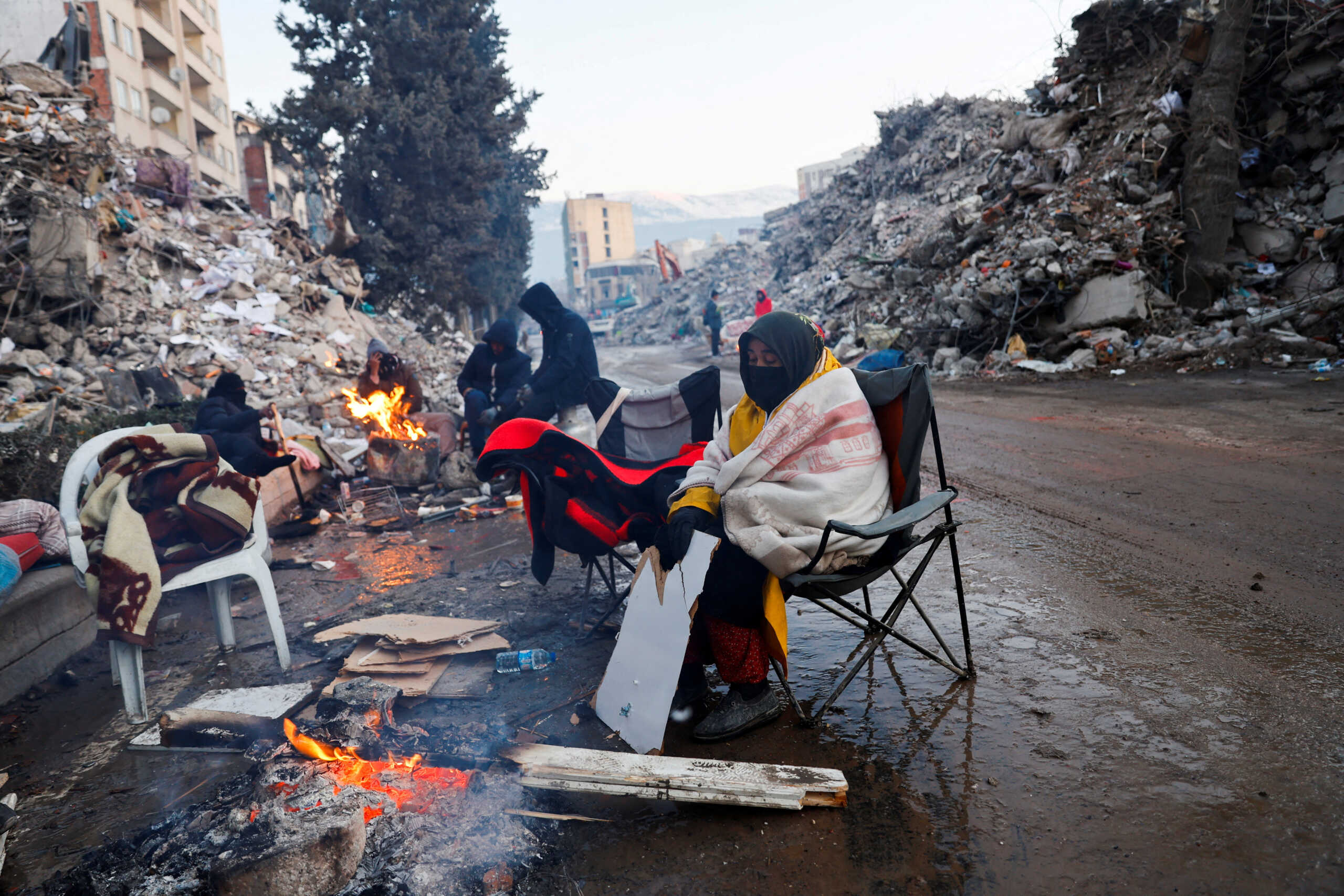 A person keeps warm by a fire as the search for survivors continues in the aftermath of a deadly earthquake in Kahramanmaras, Turkey February 13, 2023. REUTERS