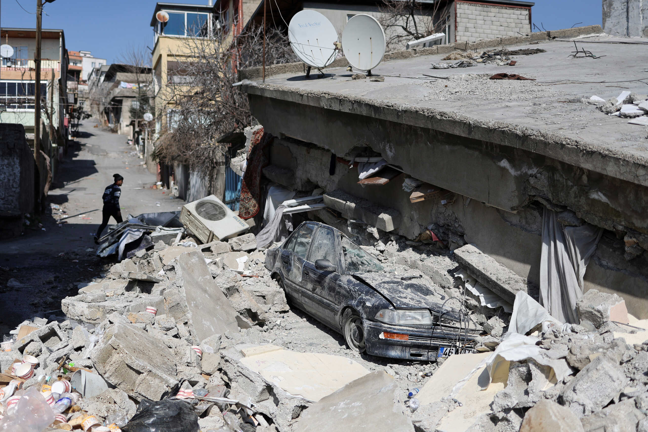 A man walks next to a collapsed house in the aftermath of a deadly earthquake in Kahramanmaras, Turkey February 14, 2023. REUTERS