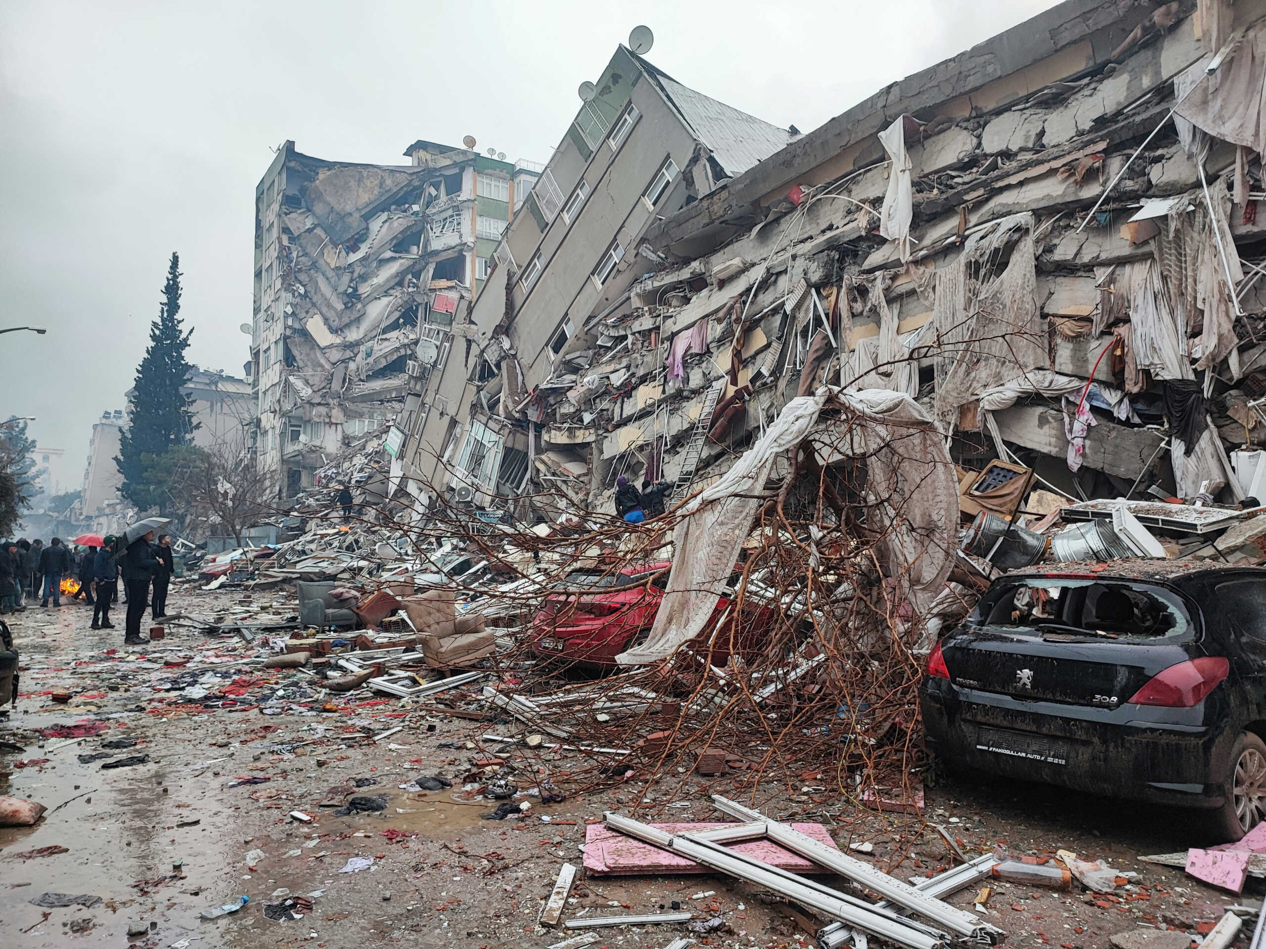 People stand in front of collapsed buildings following an earthquake in Kahramanmaras, Turkey February 6, 2023. Ihlas News Agency (IHA) via REUTERS ATTENTION EDITORS - THIS PICTURE WAS PROVIDED BY A THIRD PARTY. NO RESALES. NO ARCHIVES. TURKEY OUT. NO COMMERCIAL OR EDITORIAL SALES IN TURKEY.