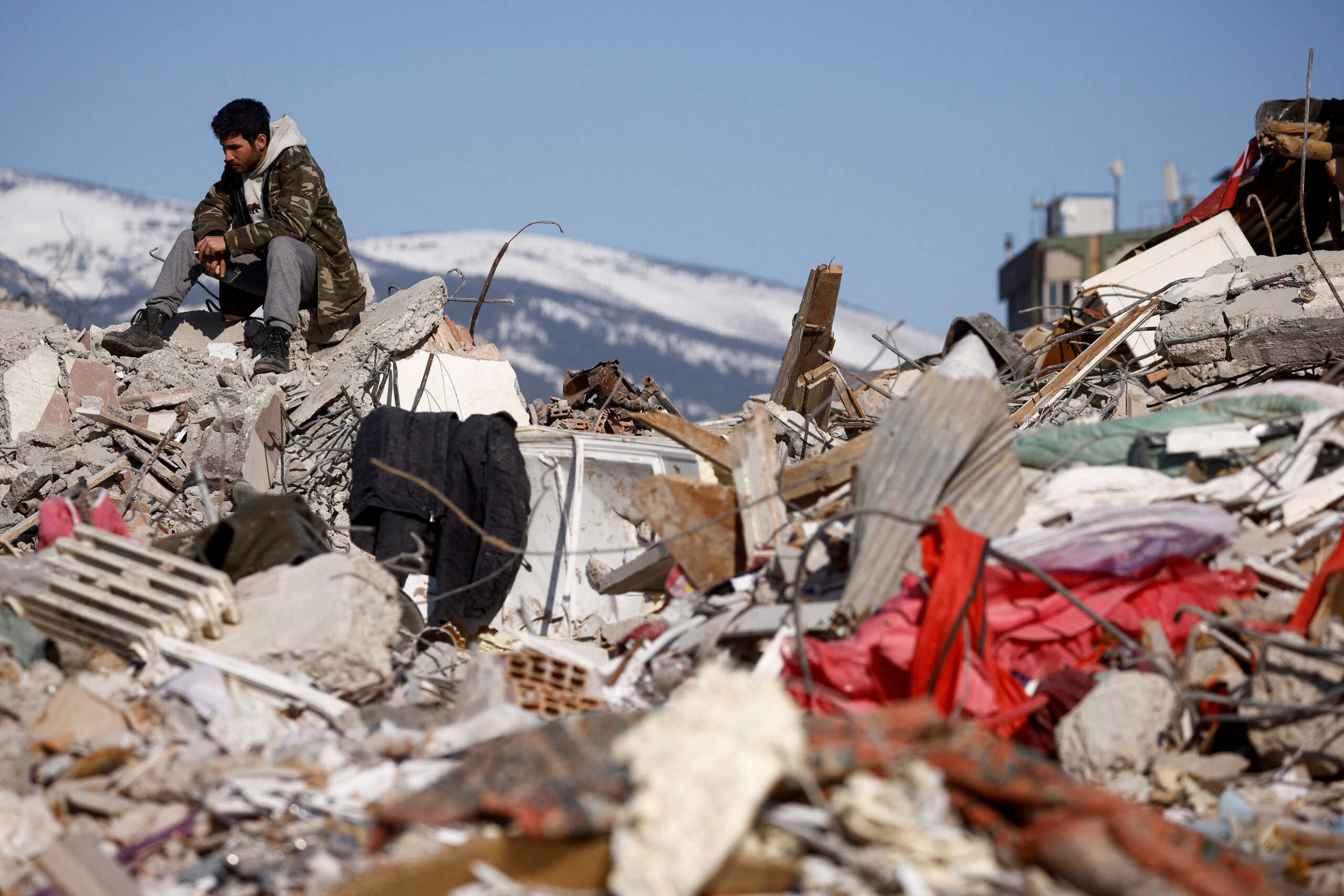 A man sits amid rubble in the aftermath of a deadly earthquake in Kahramanmaras, Turkey February 11, 2023. REUTERS