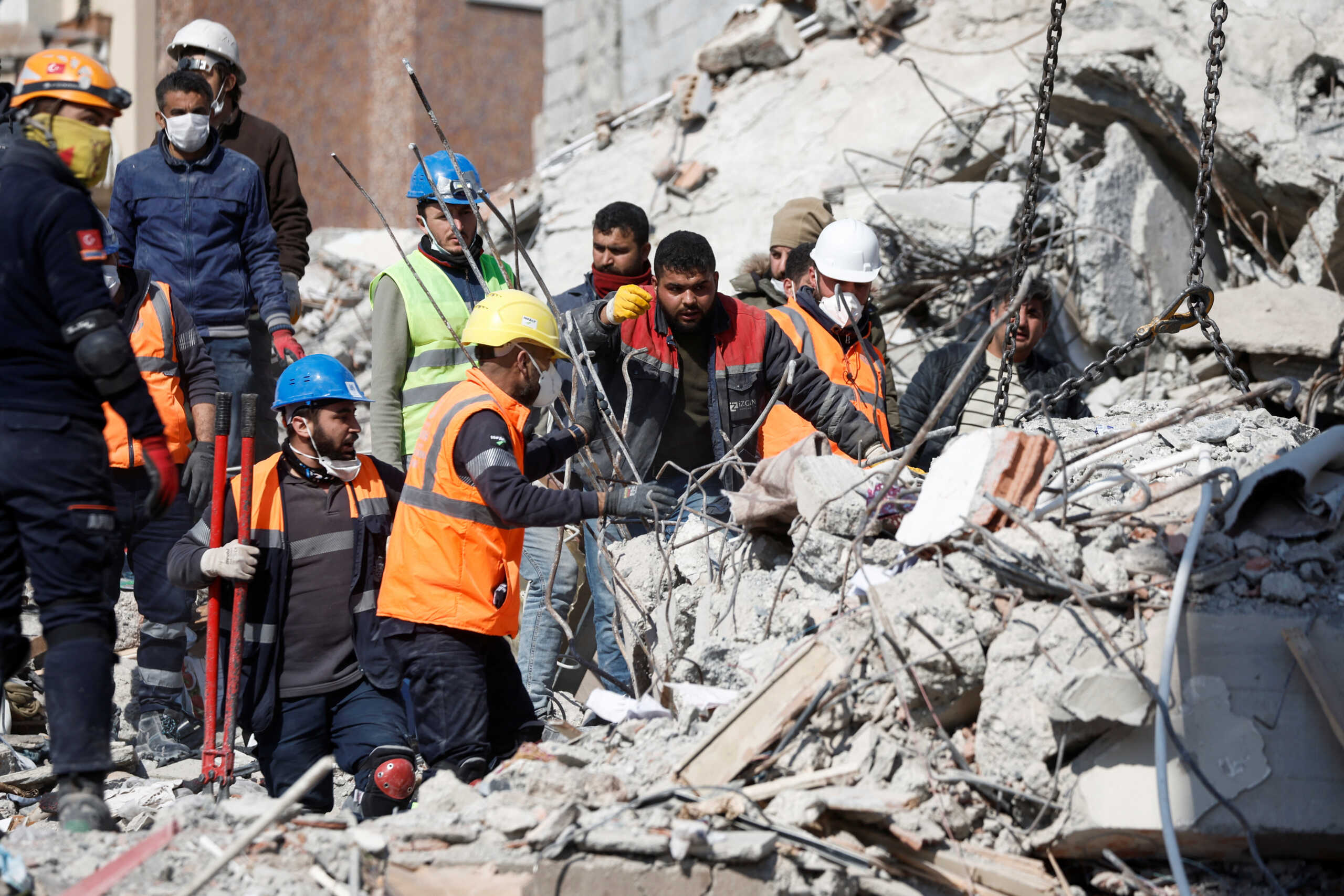 Workers stand on the rubble of demolished buildings, following the deadly earthquake in Iskenderun, Turkey, February 12, 2023. REUTERS