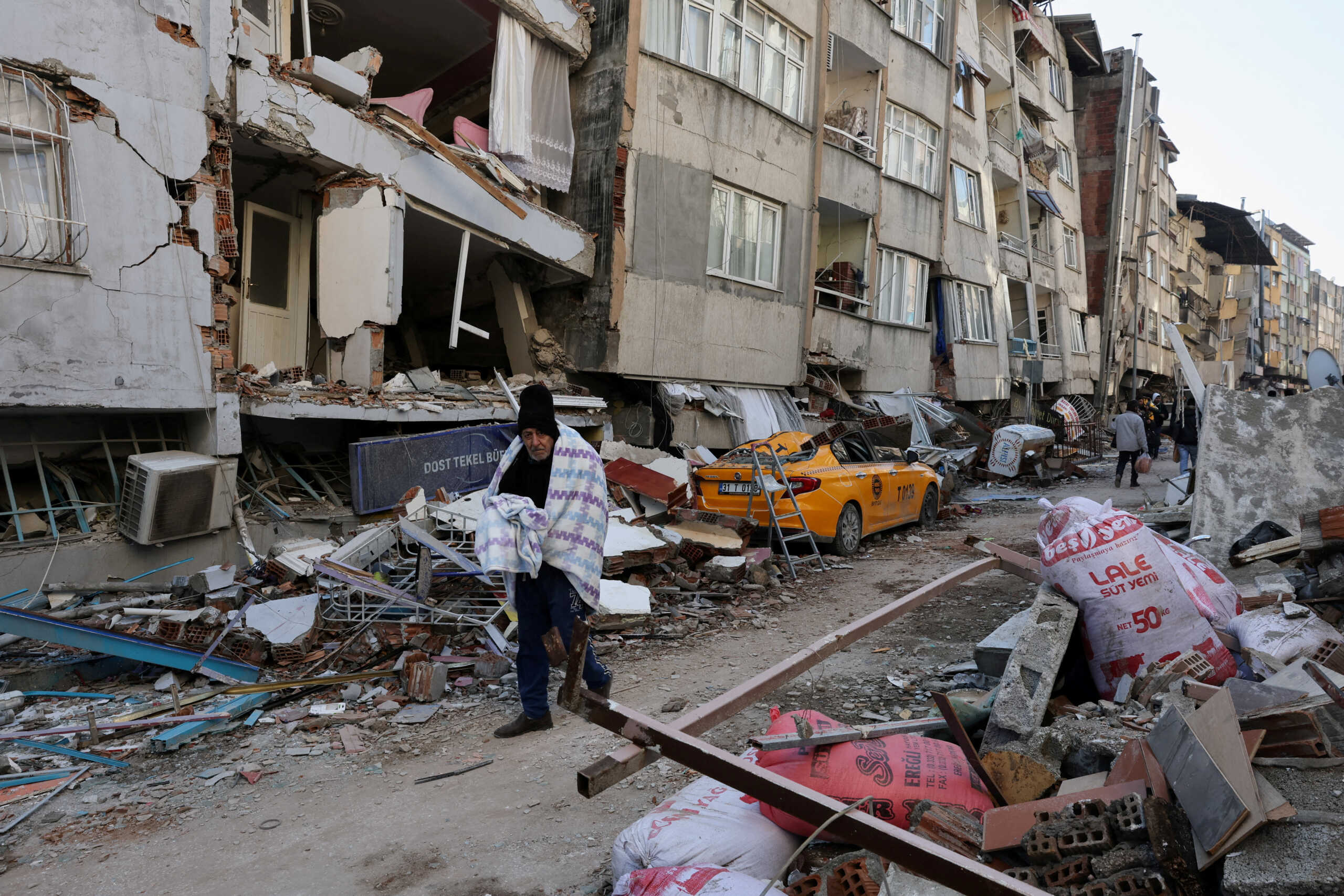 A man walks past damaged buildings as the search for survivors continues, in the aftermath of a deadly earthquake in Hatay, Turkey February 9, 2023. REUTERS