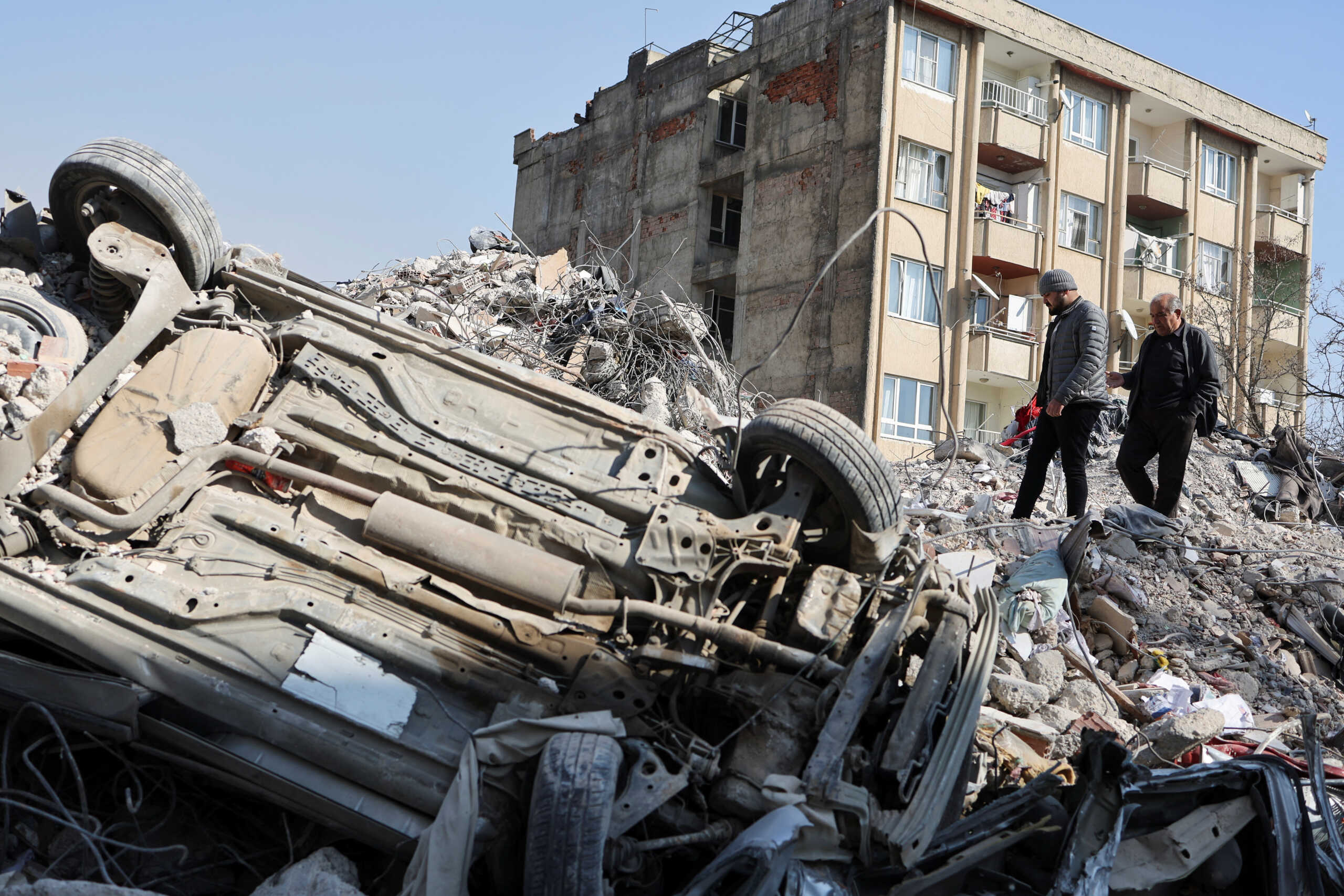 Men walk amid the rubble in the aftermath of a deadly earthquake in Kahramanmaras, Turkey February 14, 2023. REUTERS