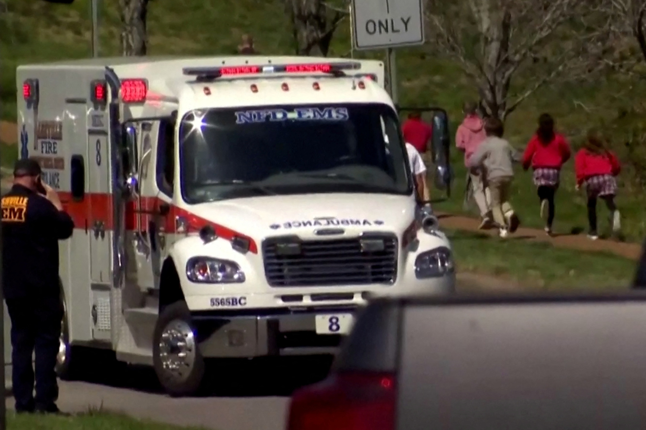 Children run past an ambulance near the Covenant School after a shooting in Nashville, Tennessee, U.S. March 27, 2023 in a still image from video.  WKRN