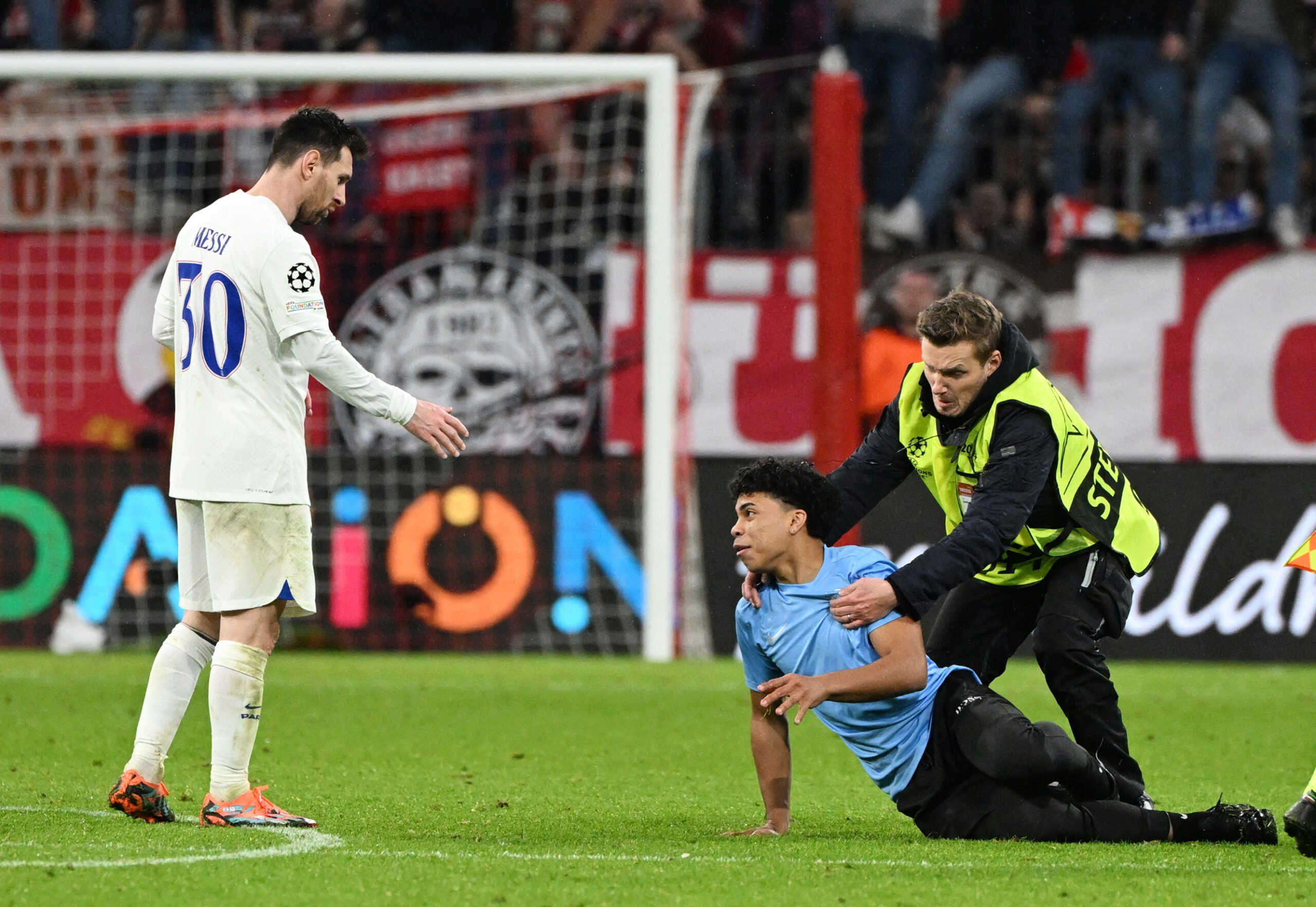 Soccer Football - Champions League - Round of 16 - Second Leg - Bayern Munich v Paris St Germain - Allianz Arena, Munich, Germany - March 8, 2023  A pitch invader is detained by a steward as Paris St Germain's Lionel Messi looks dejected after the match REUTERS