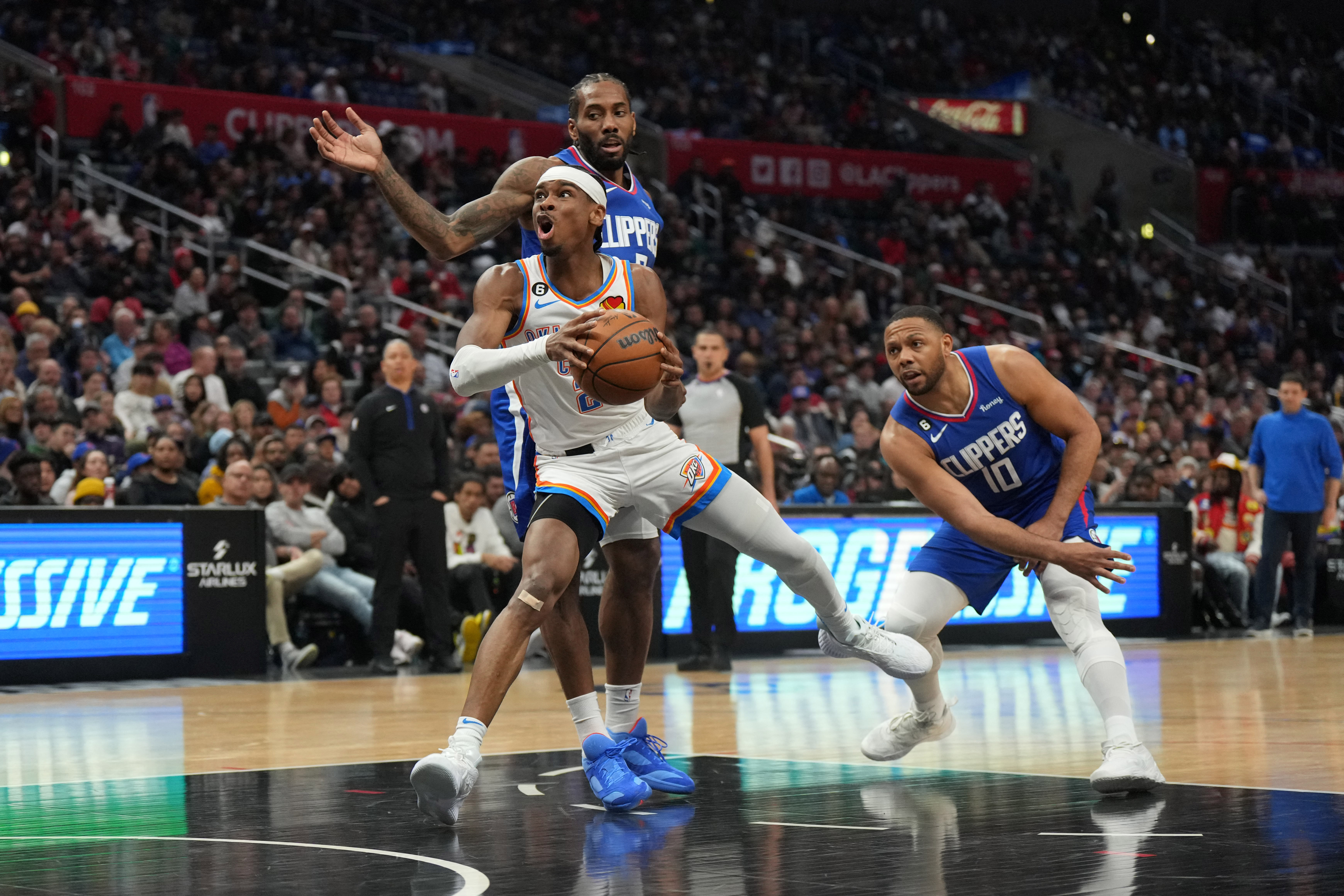 Mar 21, 2023; Los Angeles, California, USA; Oklahoma City Thunder guard Shai Gilgeous-Alexander (2) is defended by LA Clippers forward Kawhi Leonard (2) and guard Russell Westbrook (0) in the second half at Crypto.com Arena. Mandatory Credit: Kirby Lee-USA TODAY Sports