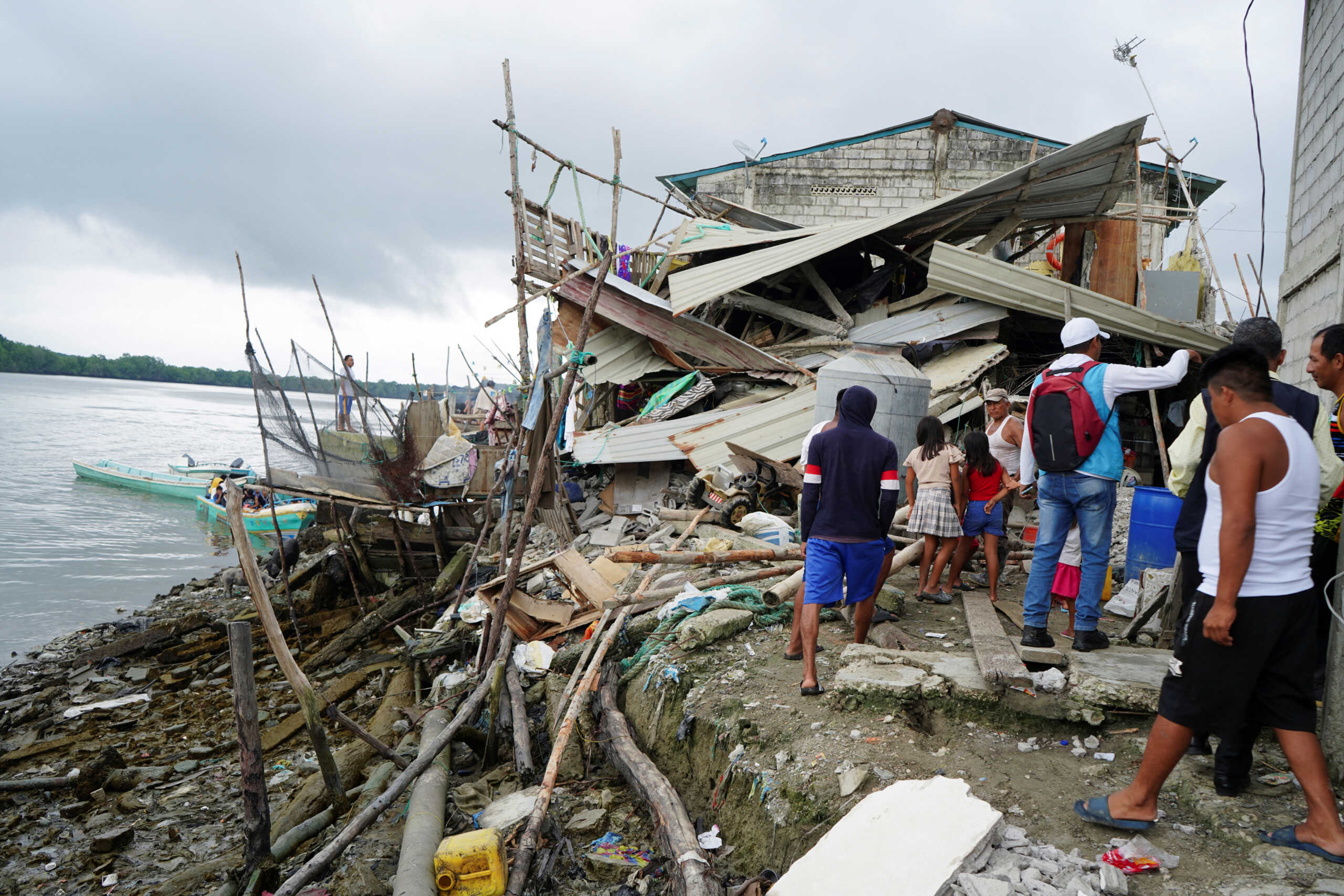 People look at a destroyed house following an earthquake in Isla Puna, Ecuador, March 19, 2023. REUTERS
