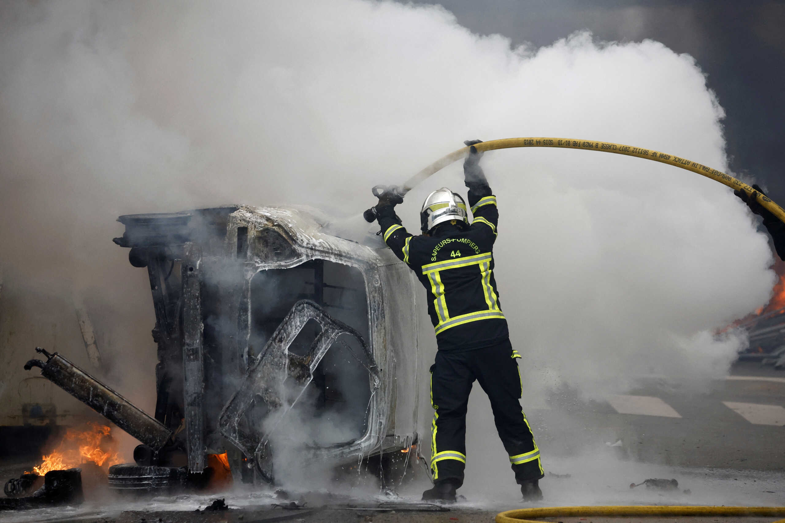 French firefighters try to extinguish a burning car during clashes at a demonstration as part of the tenth day of nationwide strikes and protests against French government's pension reform in Nantes, France, March 28, 2023.   REUTERS
