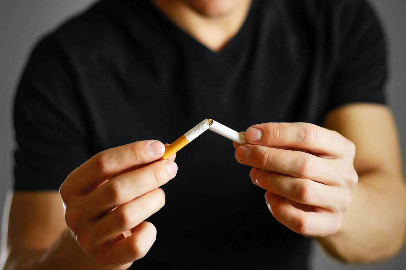 A man holds a broken cigarette in his hand. Close up. Isolated background.