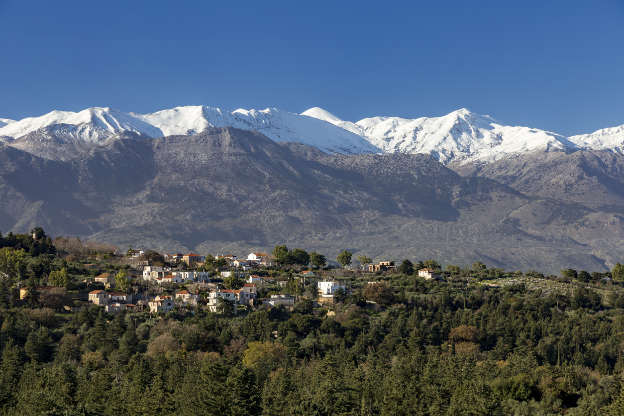 Traditional village in mountain with snowy mountains and blue sky in background. Crete Greece.