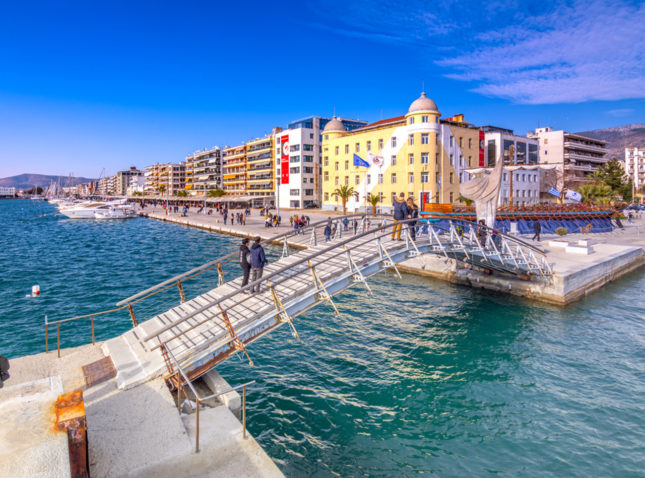 Volos, Greece – January 02, 2018: Building of the university at the seafront of Volos city with a copy of Jason’s ancient trireme.