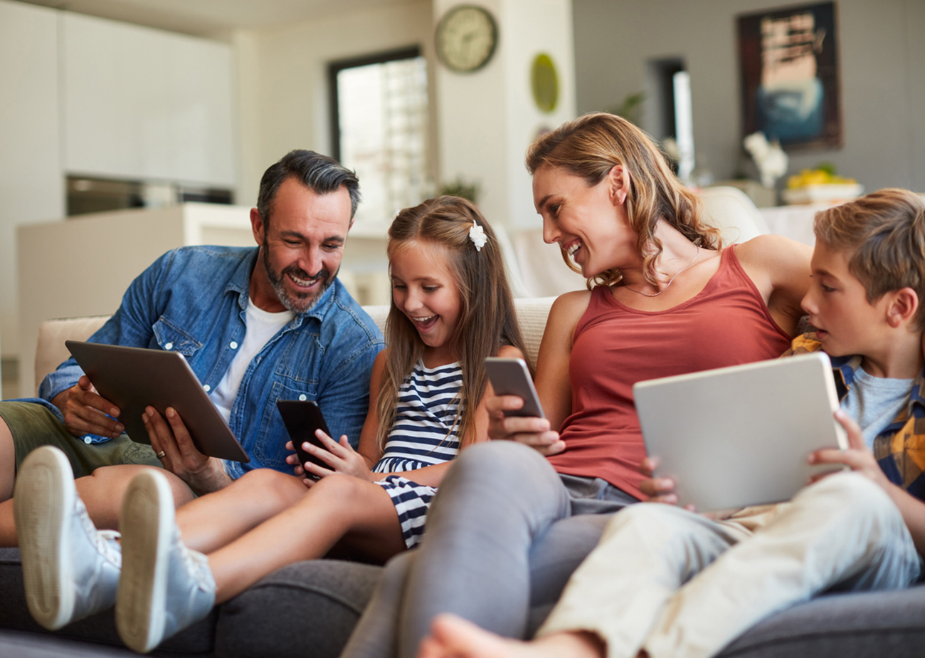 Shot of a happy young family using wireless devices on the sofa at home