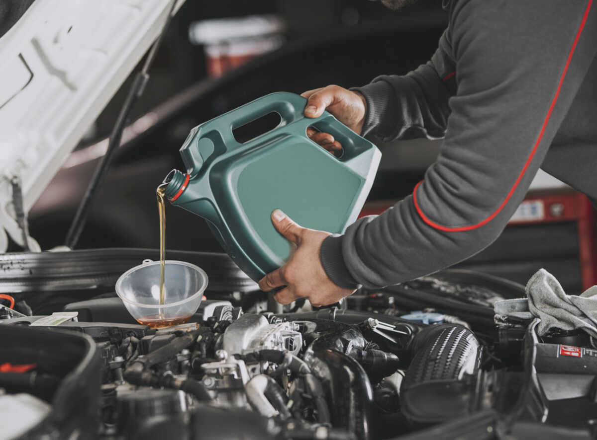 Pouring oil to car engine.