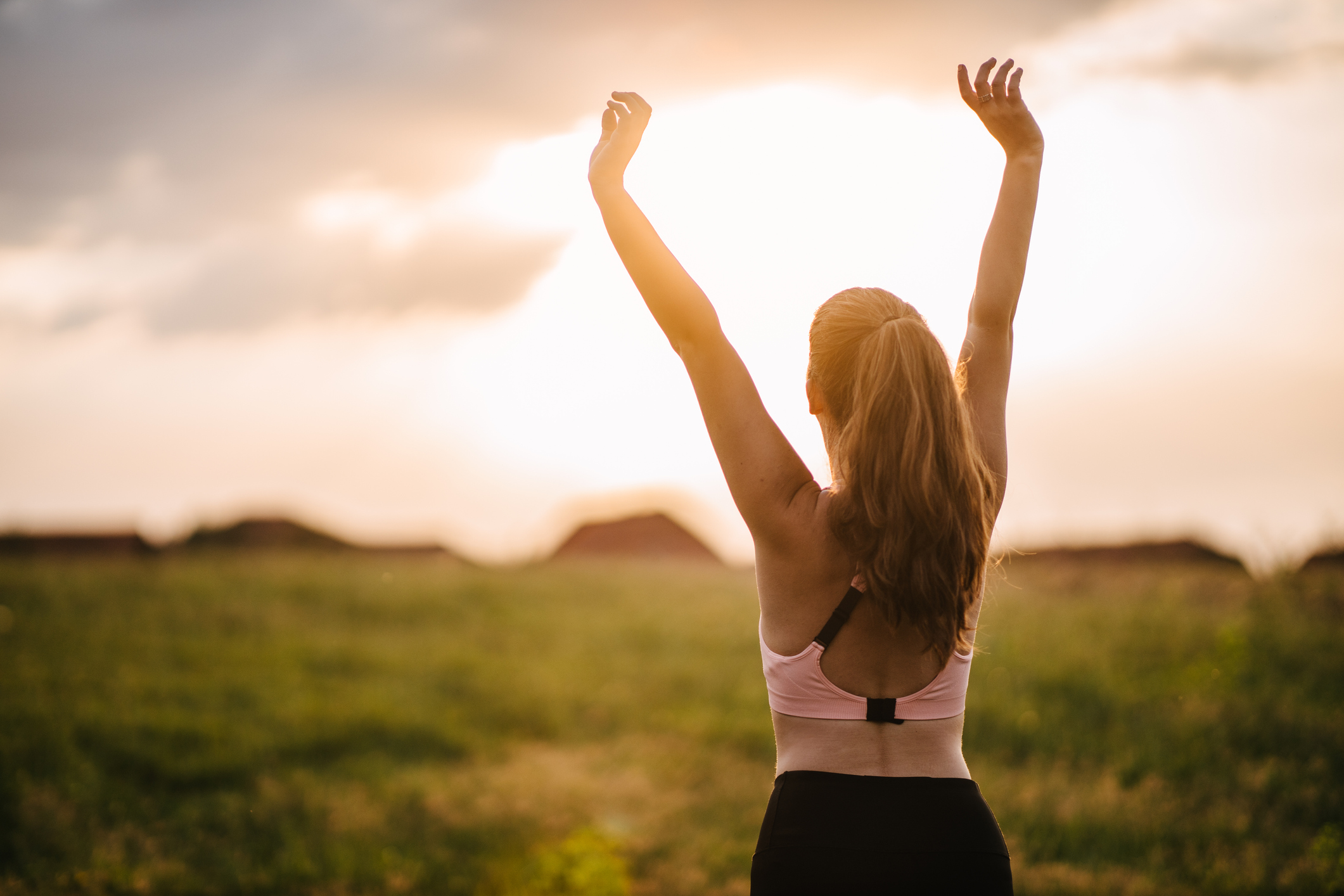 A young adult woman stretching on the meadow during her morning outdoor workout