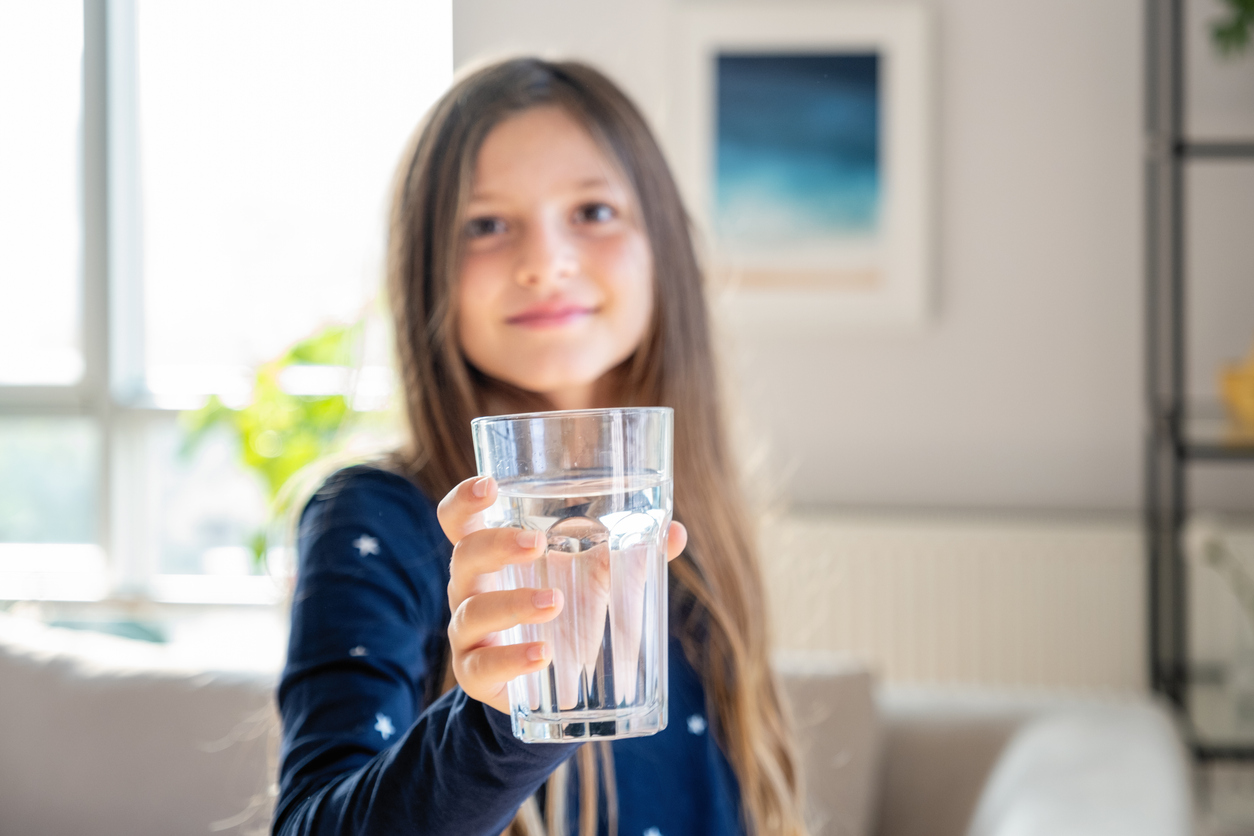 Long blond hair girl holding glass of water