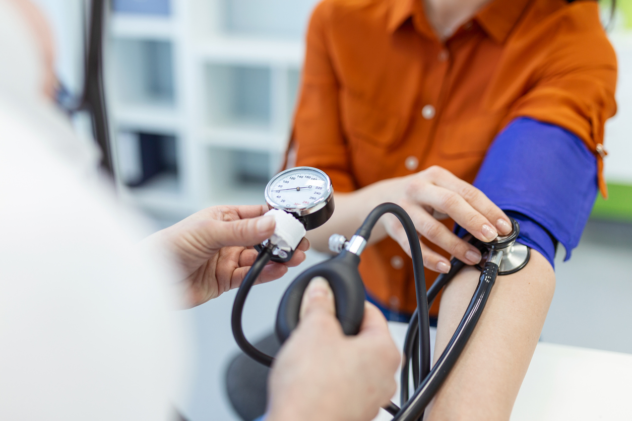 Doctor using sphygmomanometer with stethoscope checking blood pressure to a patient in the hospital.