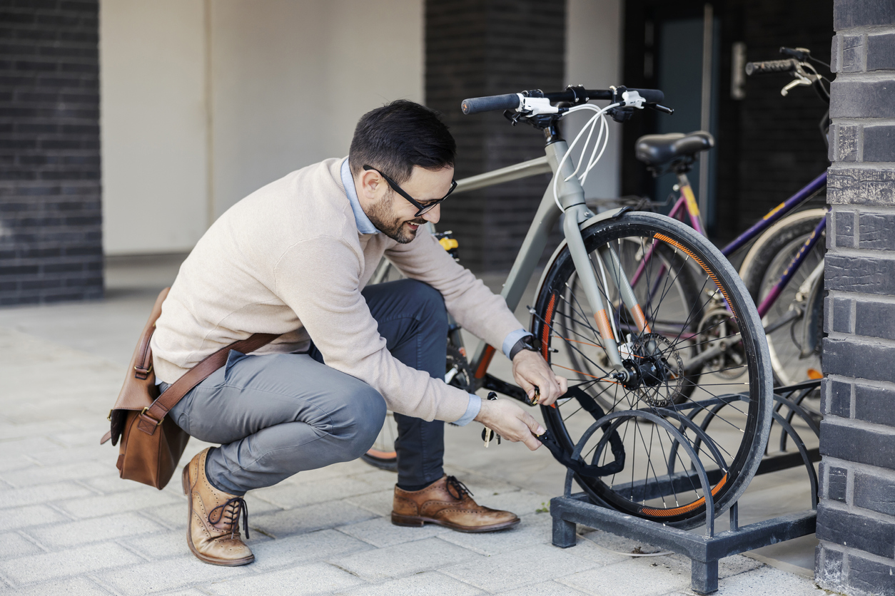 A smiling urban businessman locking up a bike on the street.