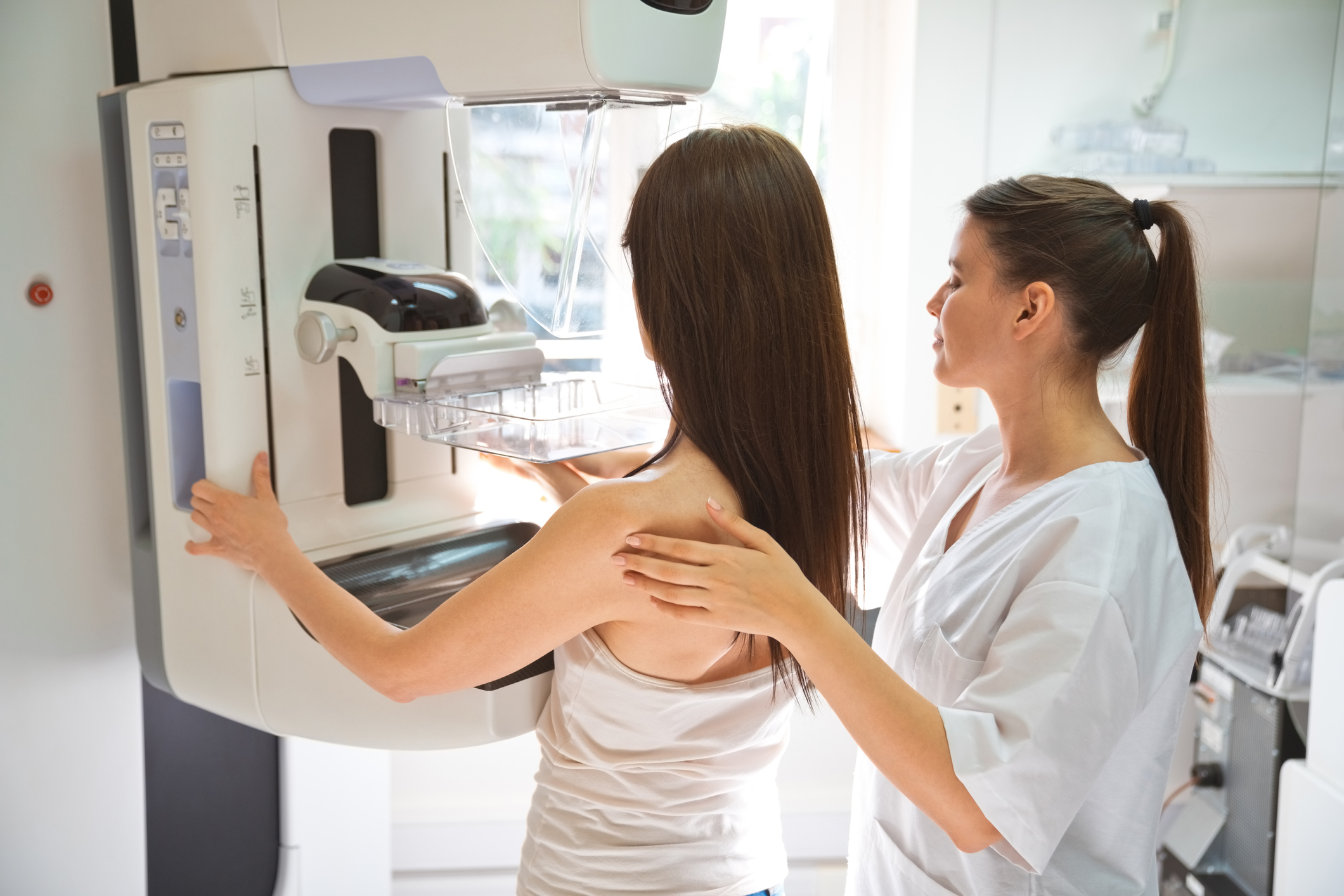 Female doctor and mid adult woman during Mammography test in examination room.