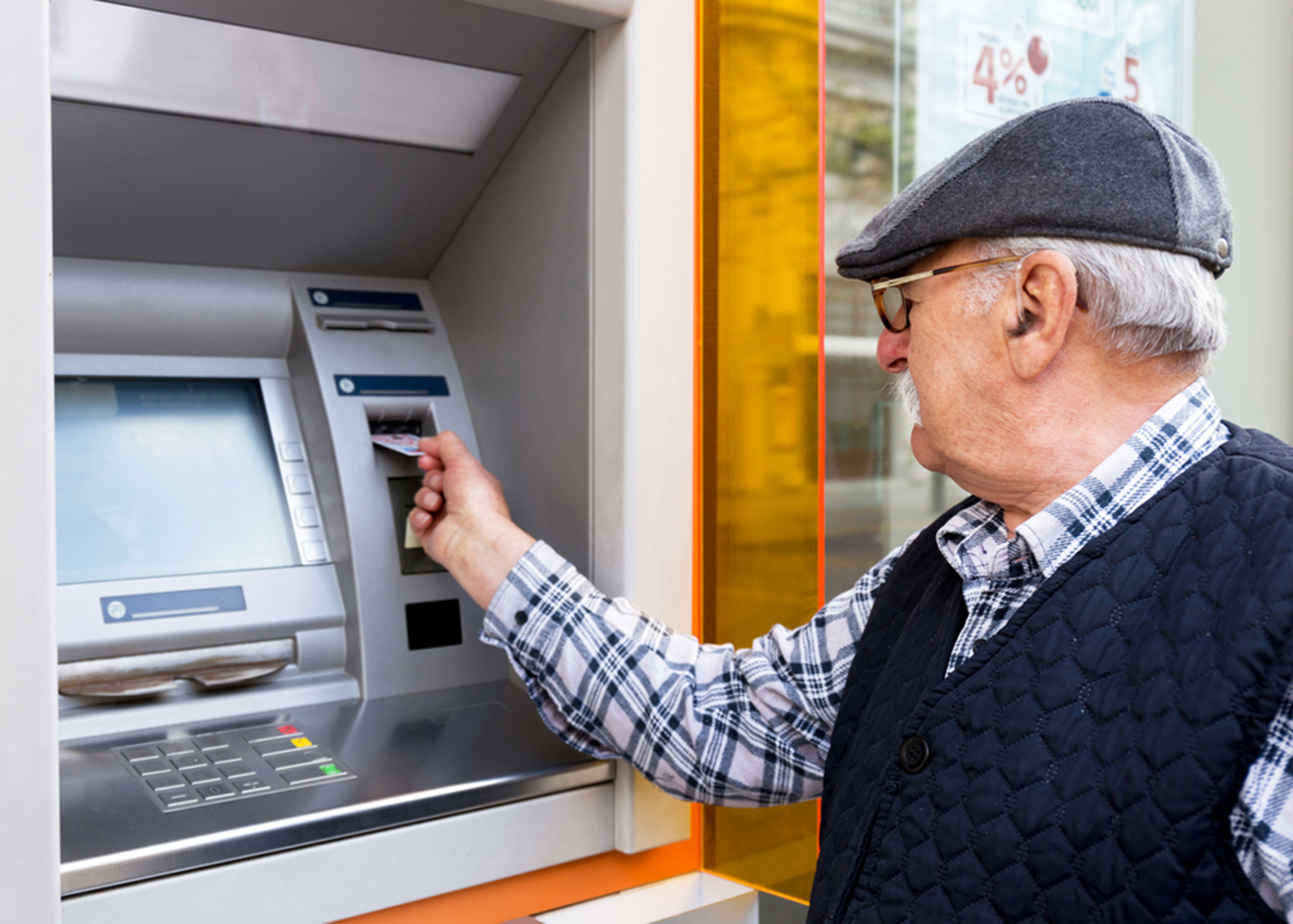elderly man inserting credit card to ATM outdoor