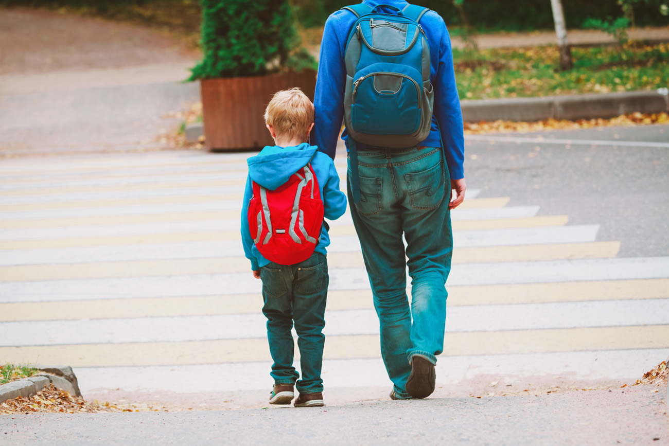 father and son go to school crossing the road, education concept