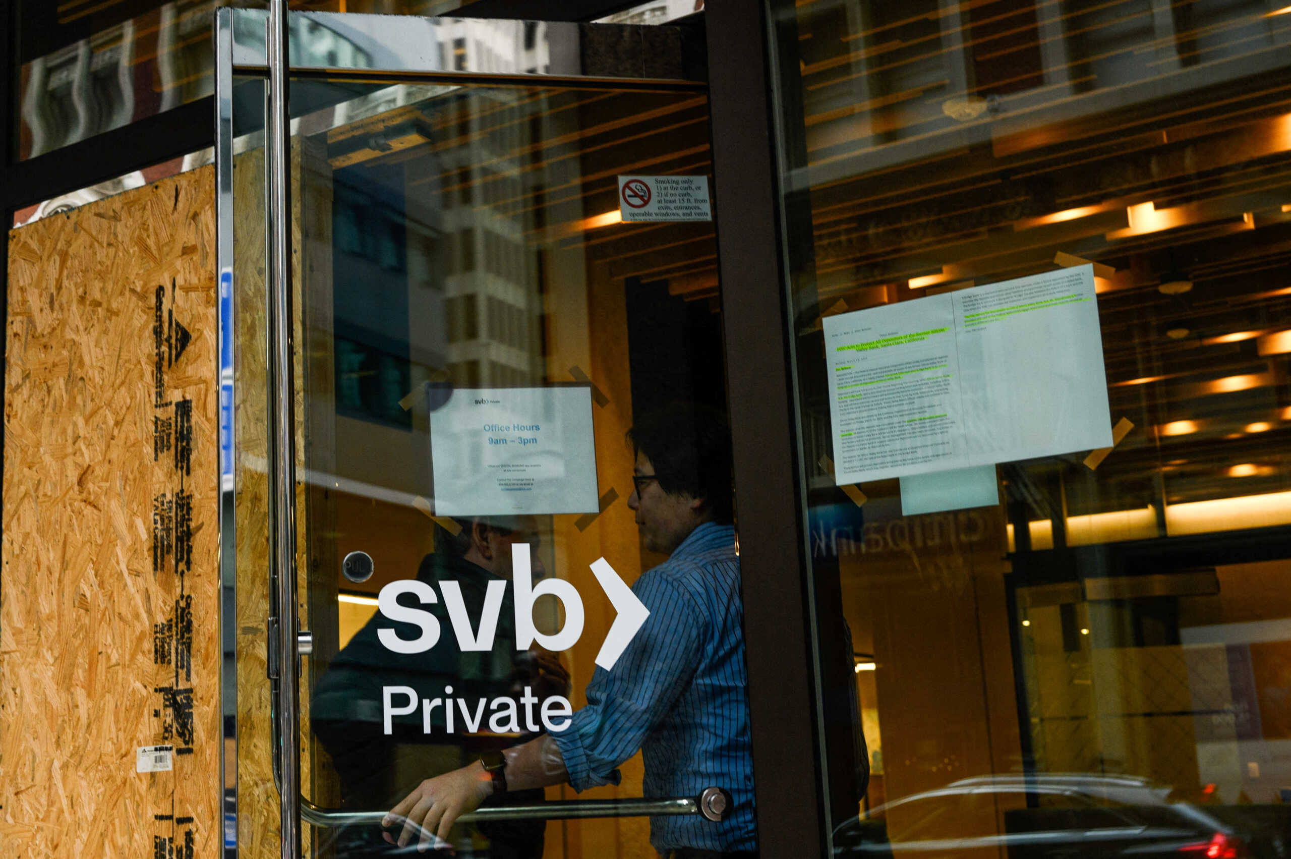 A Silicon Valley Bank employee holds the door for a customer at the bank's branch office in downtown San Francisco, California, U.S., March 13, 2023. REUTERS