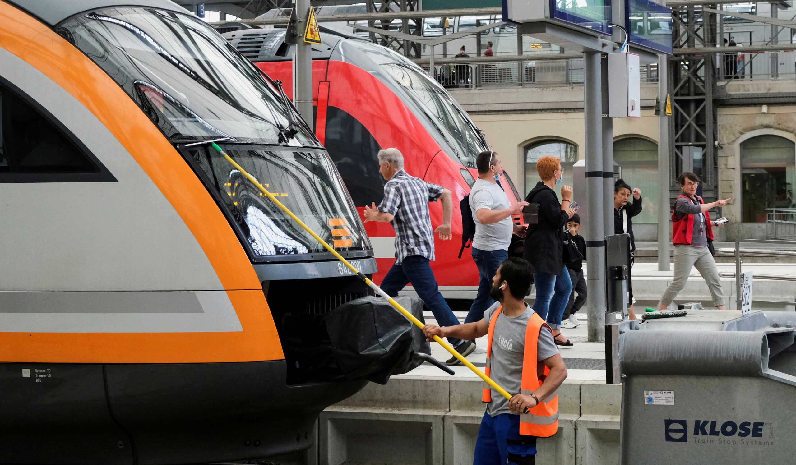 FILE PHOTO: A service employee cleans the front window of a train as passengers walk on a platform at Dresden main station after Deutsche Bahn rail operator and other local transport operators offered a special nine-euro ticket to be used nationwide for a month, in Dresden, Germany, June 4, 2022. REUTERS