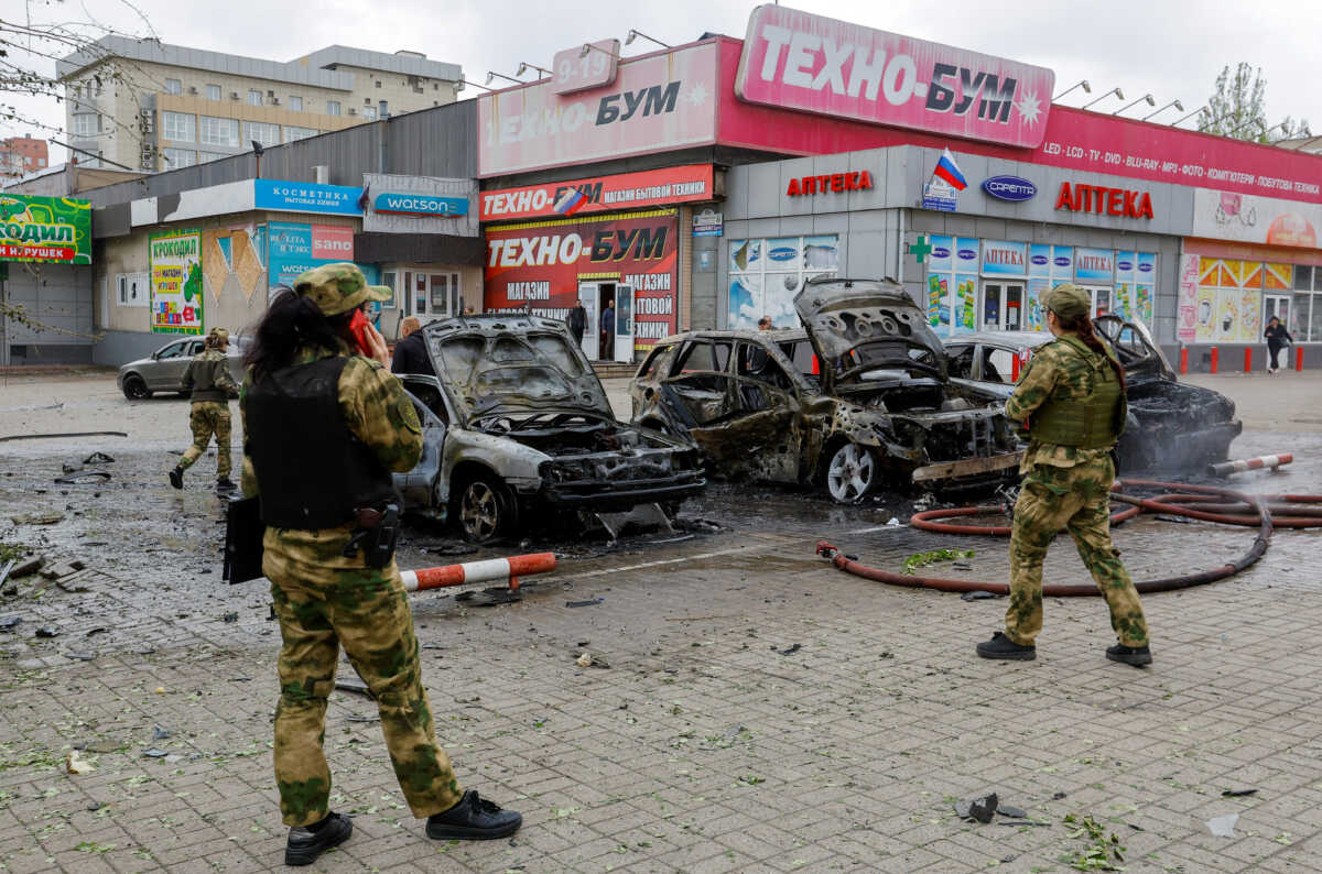 Investigators stand next to burnt-out cars while inspecting the area that was hit by shelling in the course of Russia-Ukraine conflict in Donetsk, Russian-controlled Ukraine, April 28, 2023. REUTERS